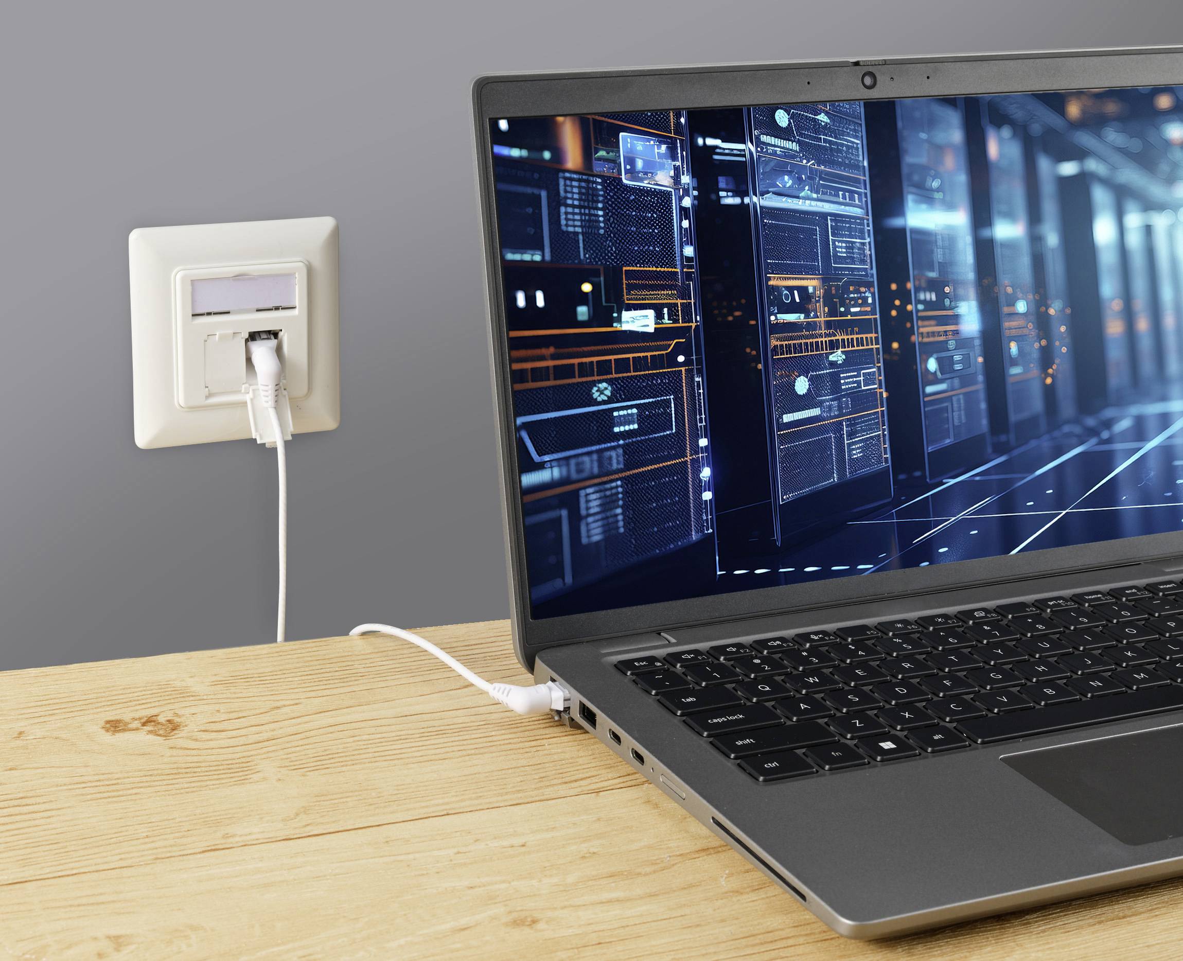 Ein geöffneter Laptop auf einem Holztisch ist mit einem Netzwerkanschluss verbunden. Auf dem Bildschirm sind technische Diagramme zu sehen.