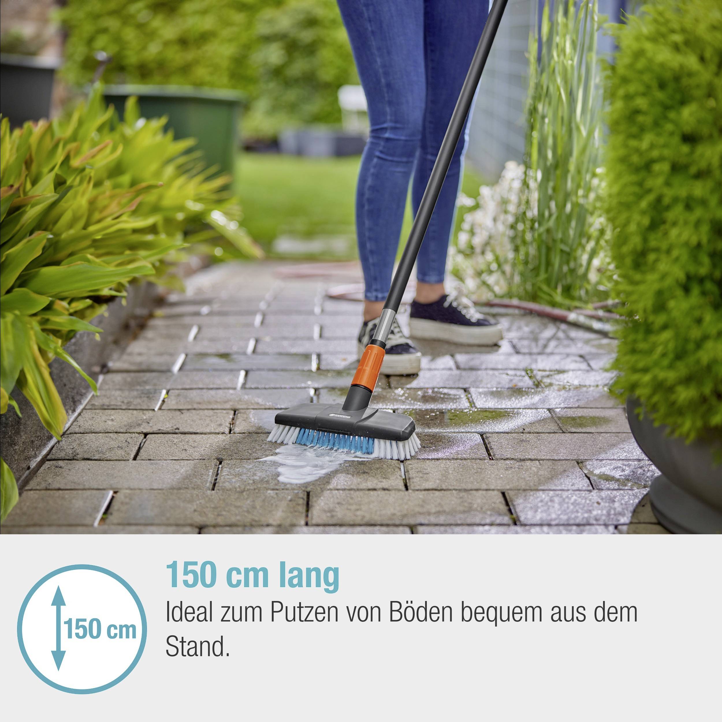 Eine Person reinigt den Boden im Freien mit einer Bürste an einem langen Stiel. Text im Bild: '150 cm lang. Ideal zum Putzen von Böden bequem aus dem Stand.'