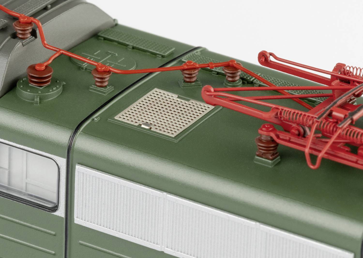 Obenansicht einer grünen Modelllokomotive mit sichtbaren roten Stromabnehmern und Details der Dachstruktur.