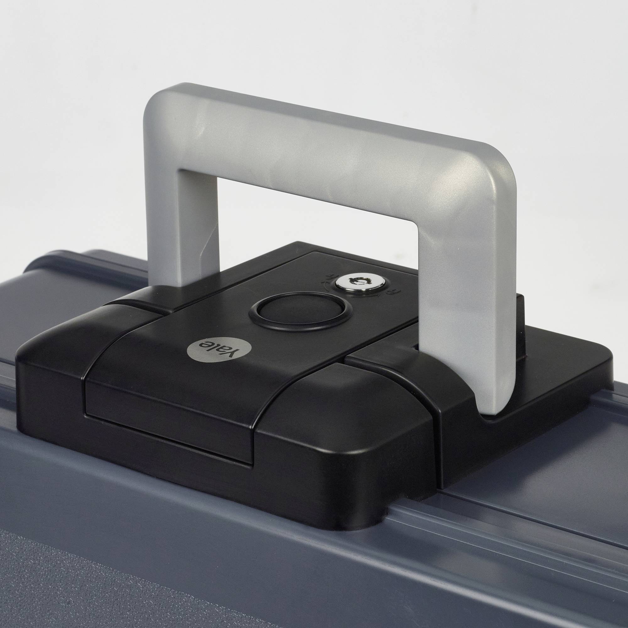 Schwarzer Koffergriff mit Schlüsselloch und rundem Logo auf einem grauen Koffer.