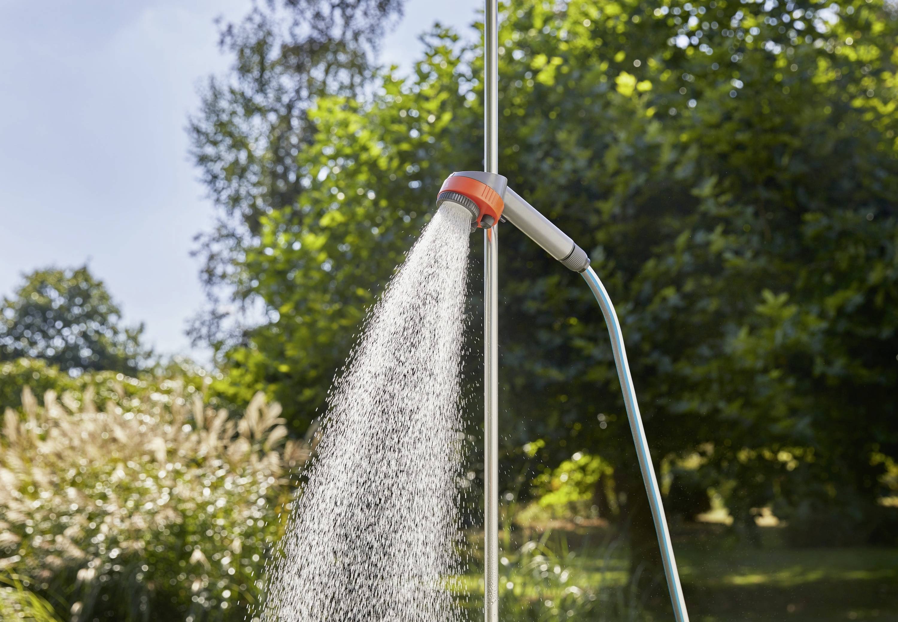 Outdoor-Dusche mit fließendem Wasser, umgeben von Grün, unter klarem Himmel