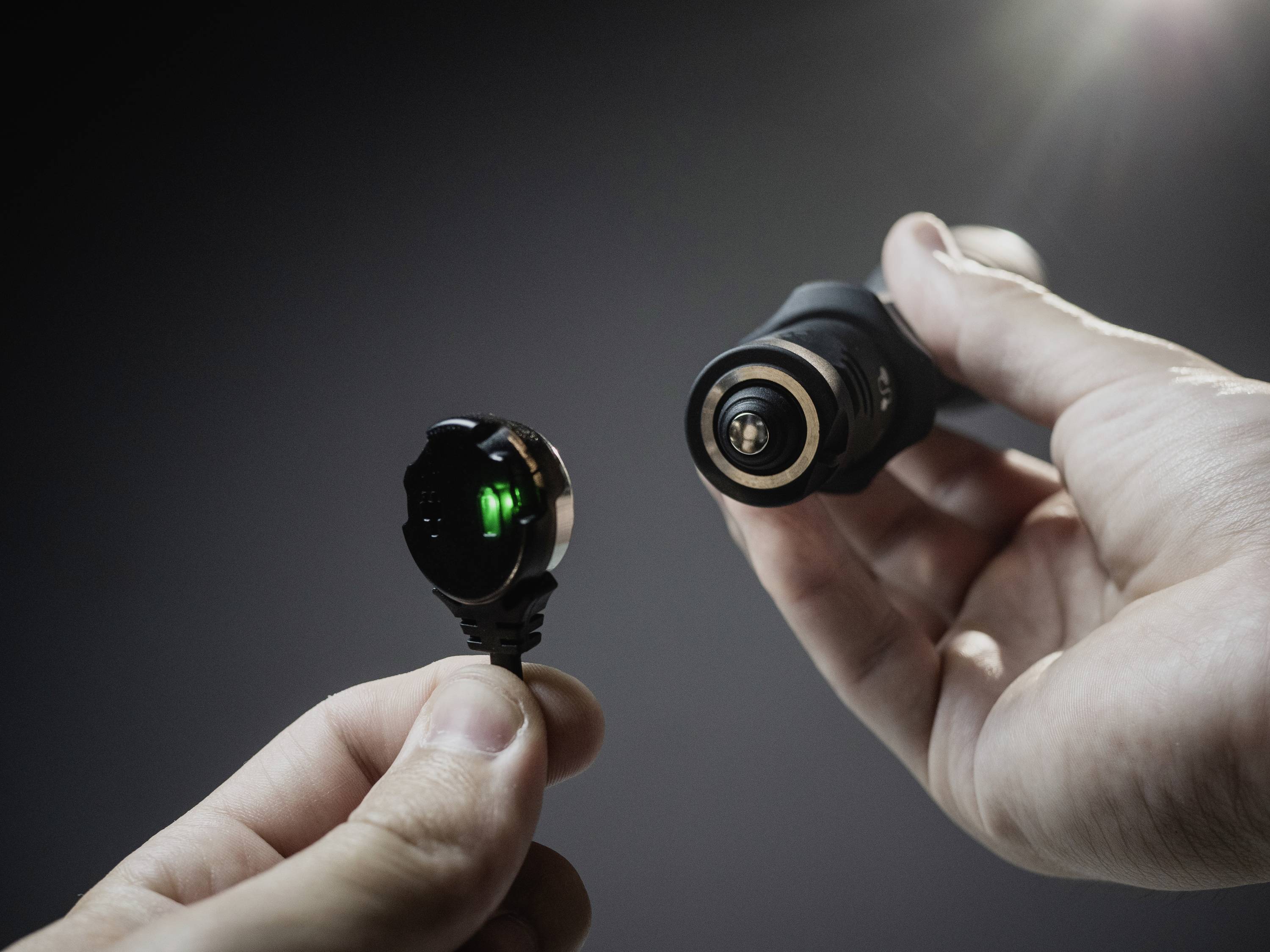 Eine Hand hält einen elektrischen Anschluss mit grünem Licht, die andere ein kabelloses Mikrofon, bereit zum Verbinden.