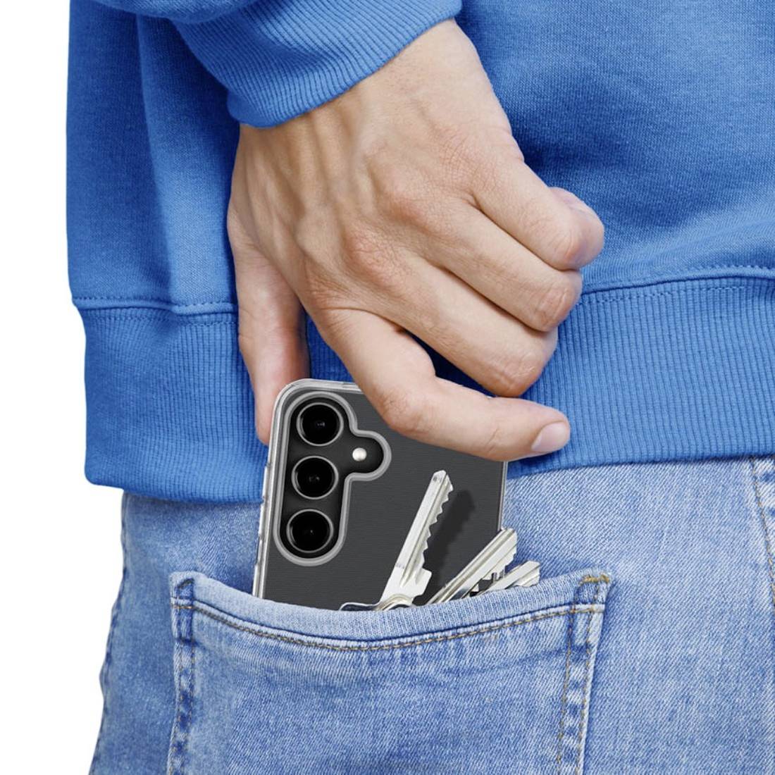 Eine Hand steckt ein Smartphone mit Schlüsseln in die Gesäßtasche einer blauen Jeans.