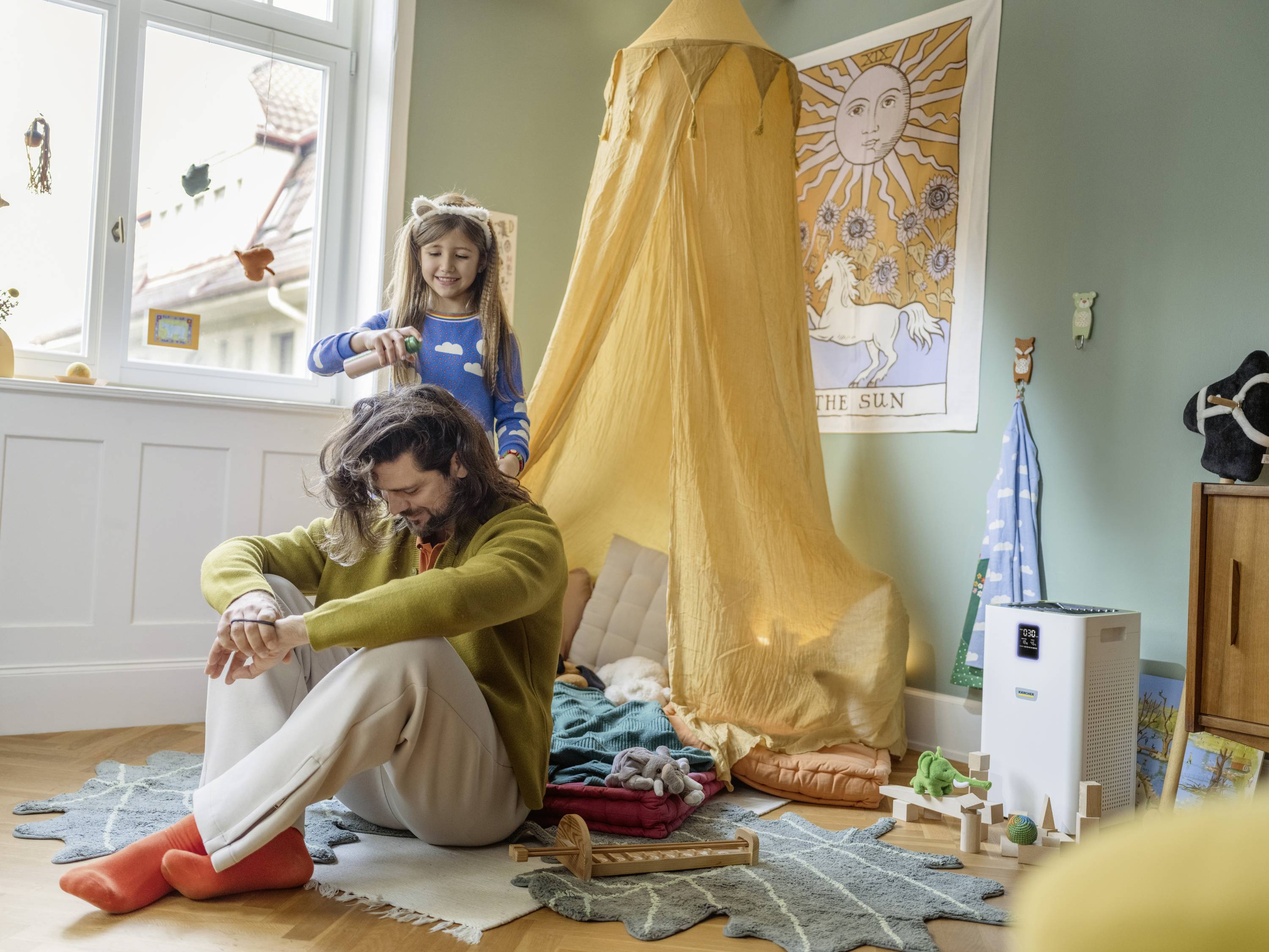 Ein Mädchen frisiert das Haar eines Mannes in einem gemütlichen Kinderzimmer mit Baldachin und Spielzeug.