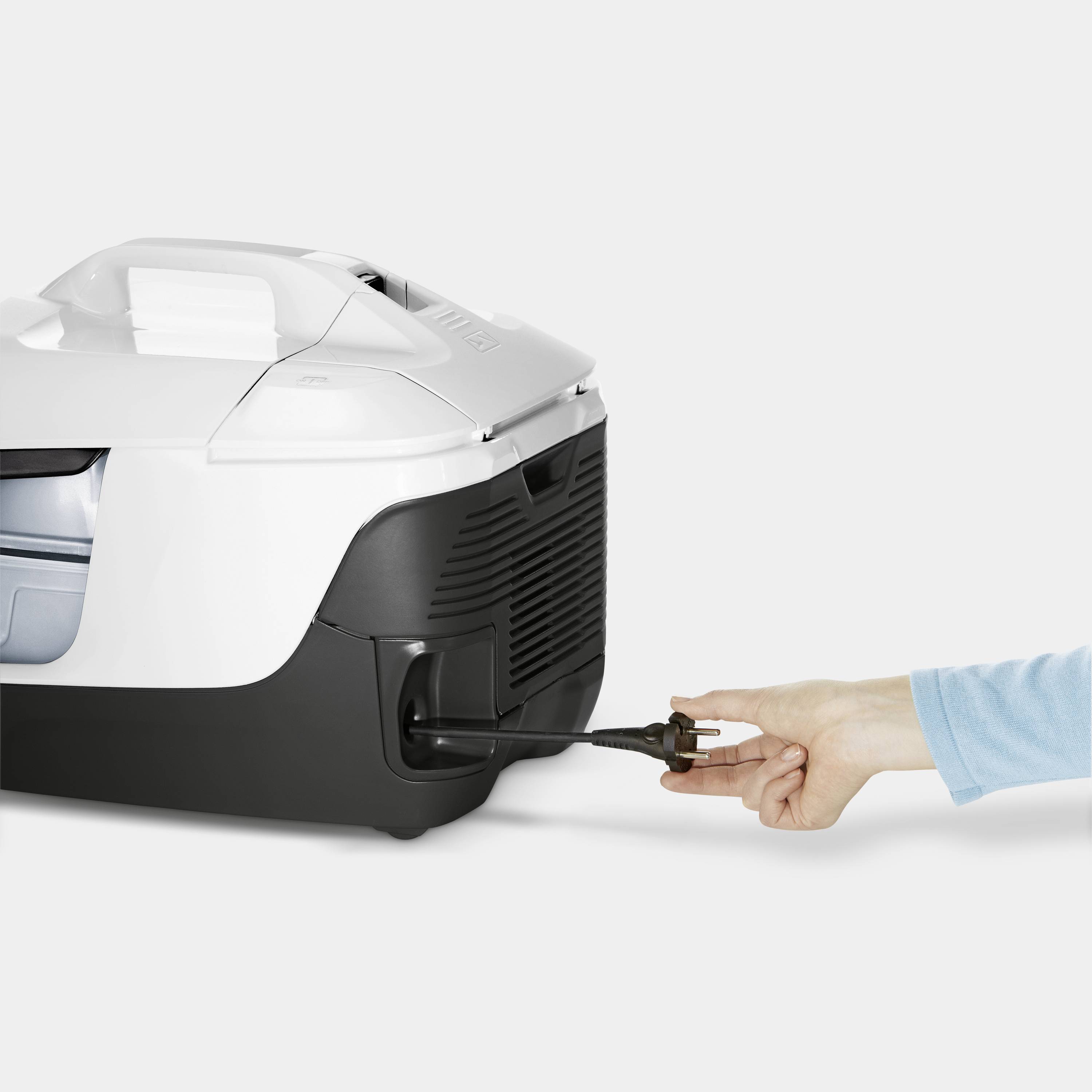 Eine Person hält eine Steckverbindung an einem weißen und schwarzen Gerät, das wie ein Behälter oder eine Maschine aussieht.