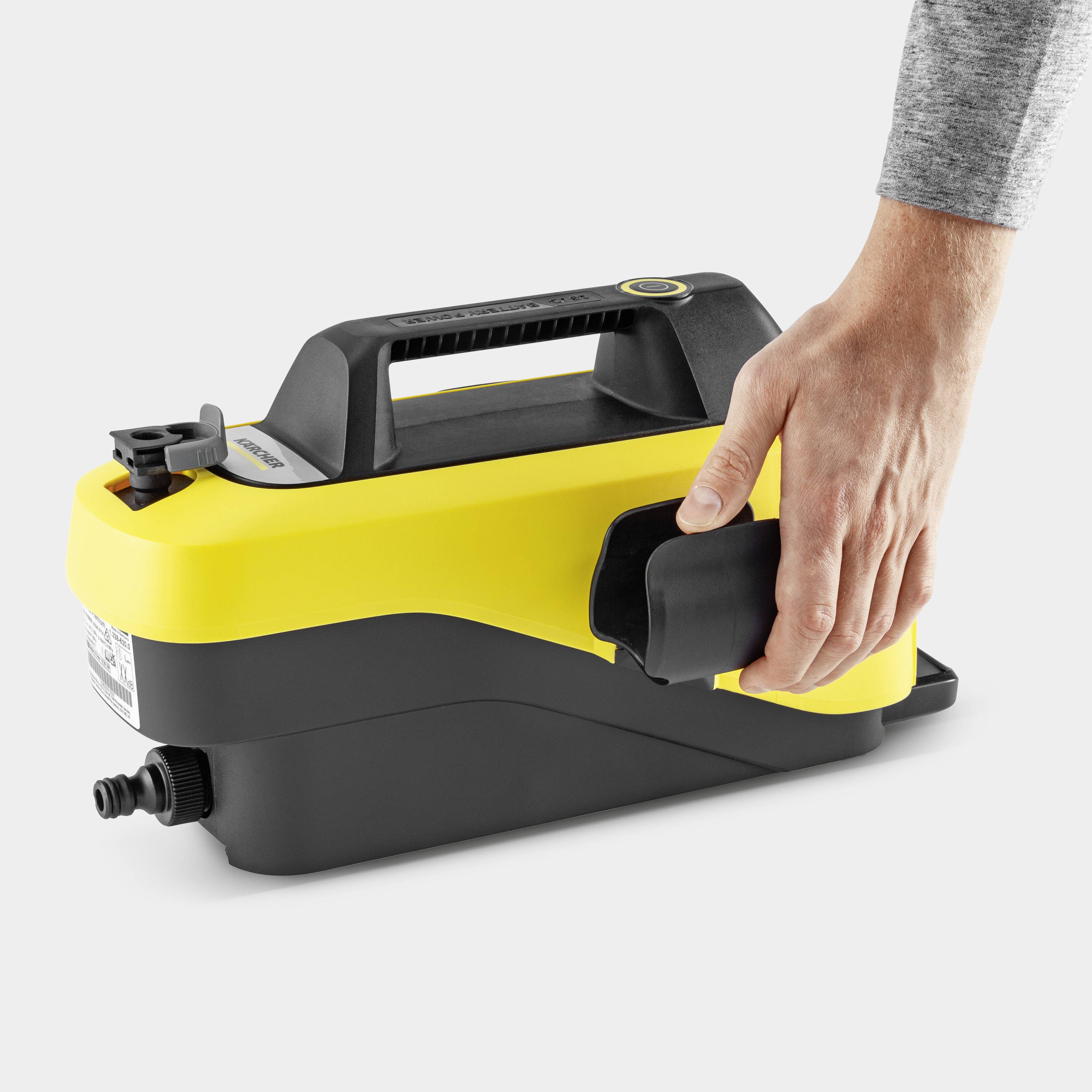 Eine Hand greift den Griff eines tragbaren gelb-schwarzen Hochdruckreinigers auf weißem Hintergrund.