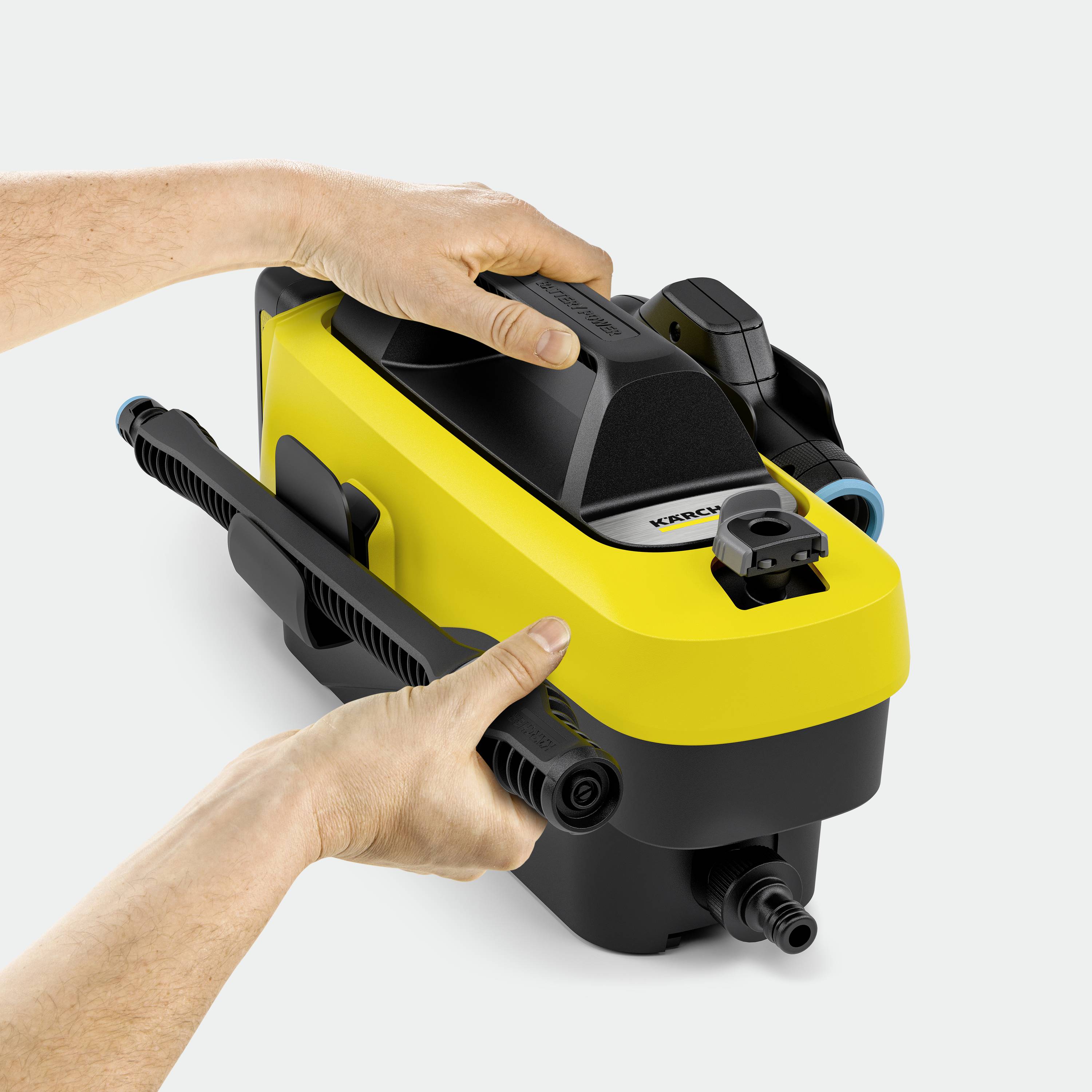 Zwei Hände halten einen gelben Hochdruckreiniger mit schwarzem Griff, geeignet für Reinigungsanwendungen im Außenbereich.