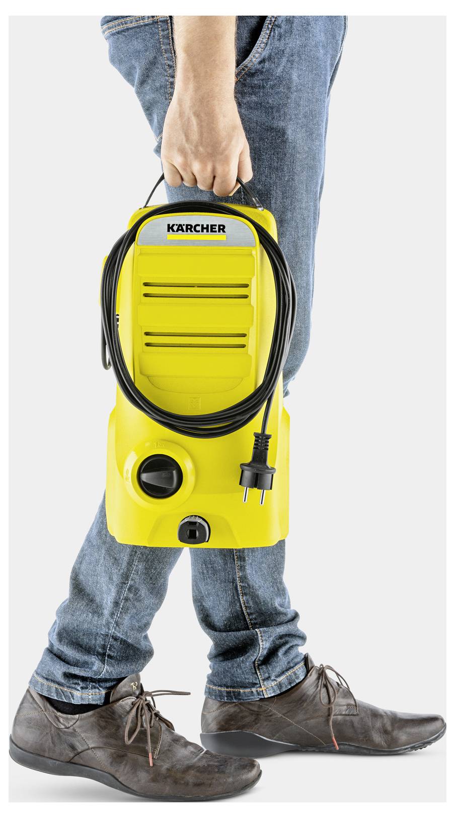 Eine Person trägt einen gelben Kärcher-Hochdruckreiniger an seinem Griff und demonstriert damit seine Tragbarkeit. Das Netzkabel ist ordentlich um das Gerät gewickelt.