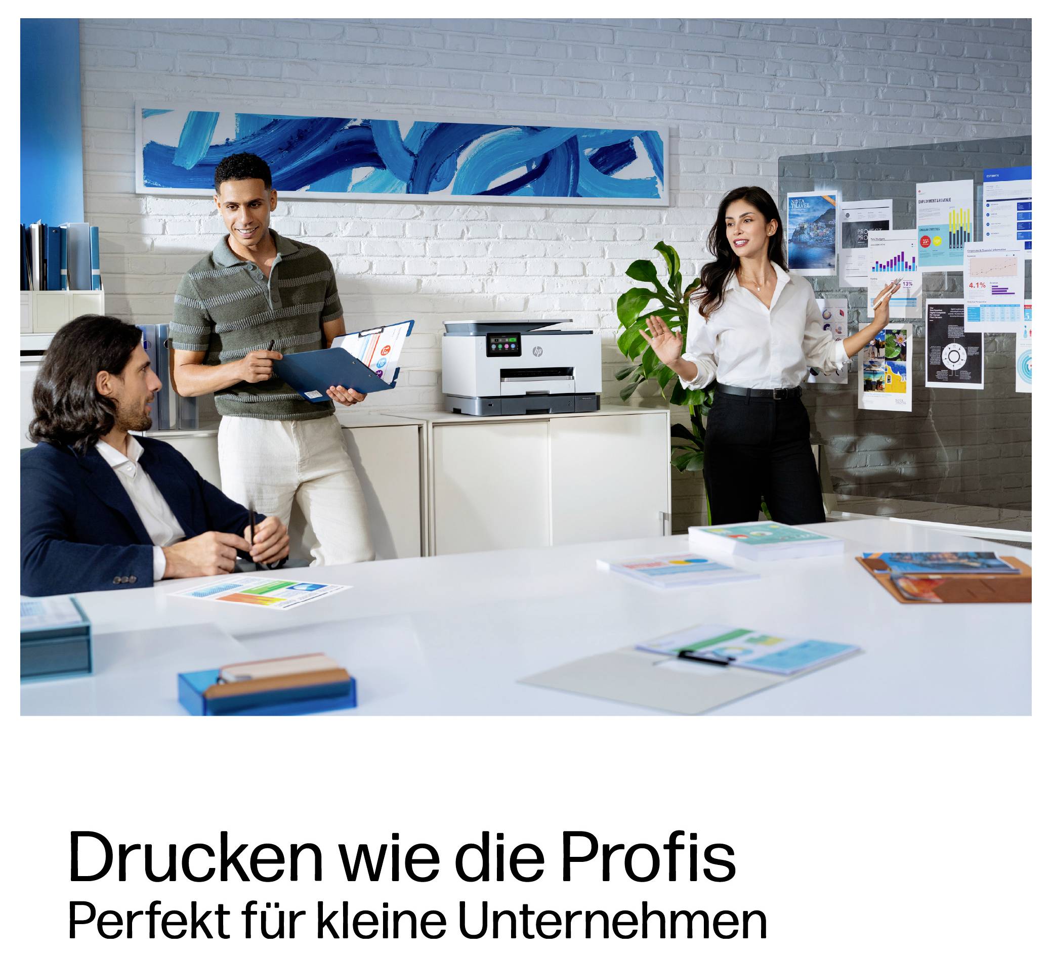 Drei Kollegen diskutieren in einem Büro über Diagramme, mit einem Drucker auf einem Schrank; deutscher Text sagt „Drucken wie die Profis" und „Perfekt für kleine Unternehmen".