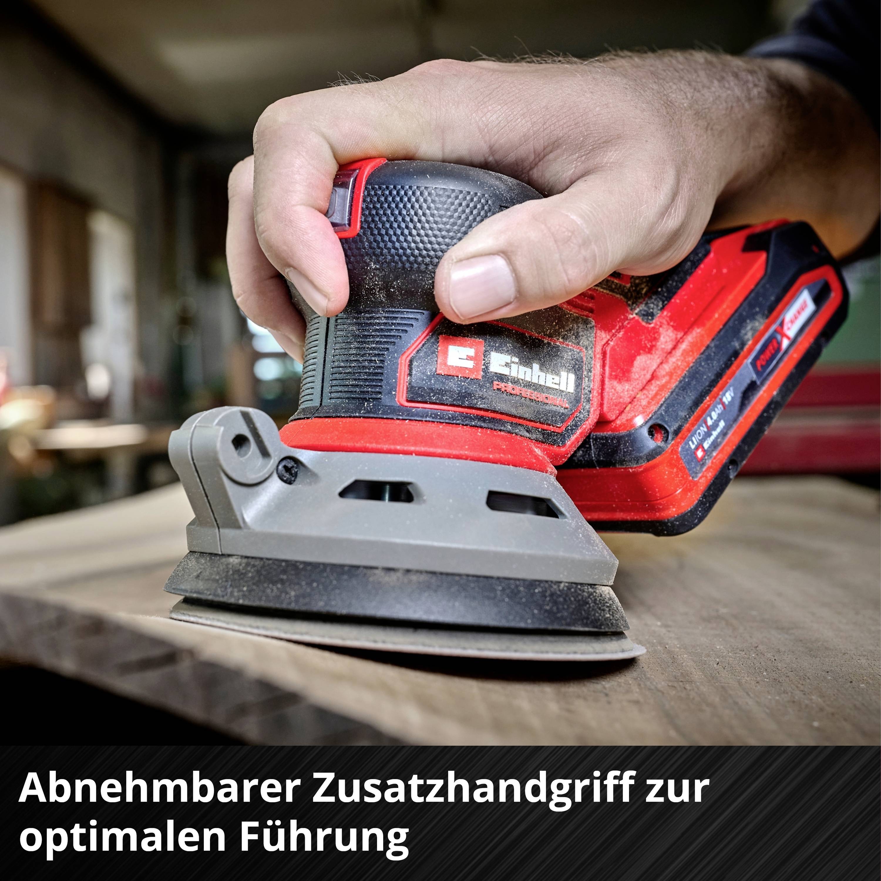 Eine Hand hält einen rot-schwarzen Schwingschleifer auf einem Holzbrett. Unten steht: 'Abnehmbarer Zusatzhandgriff zur optimalen Führung'.