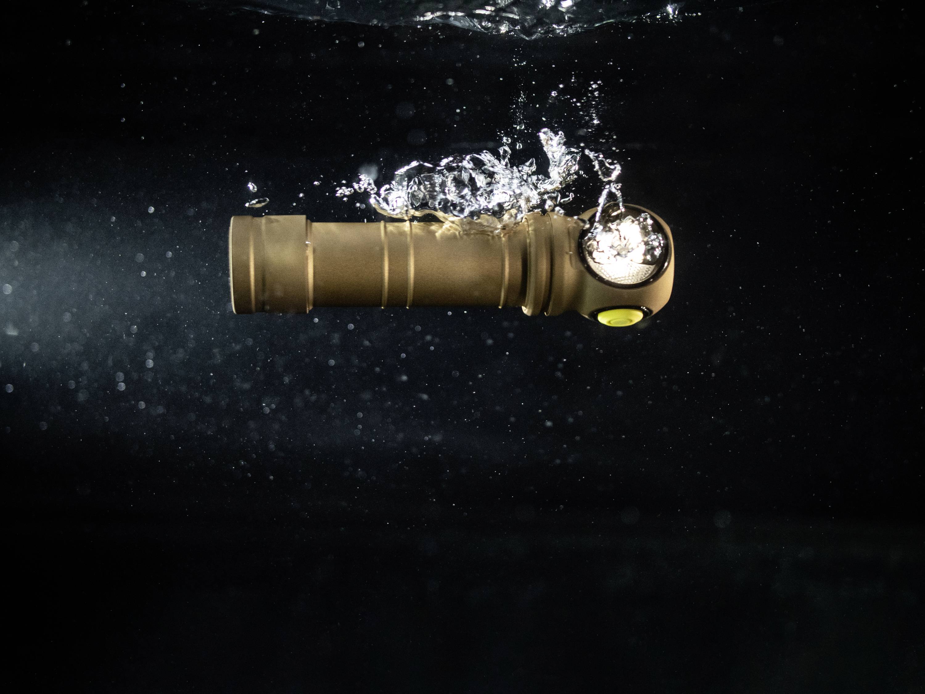 Taschenlampe unter Wasser mit eingeschaltetem Licht, Luftblasen steigen auf. Sie zeigt Langlebigkeit und Wasserdichtigkeit.