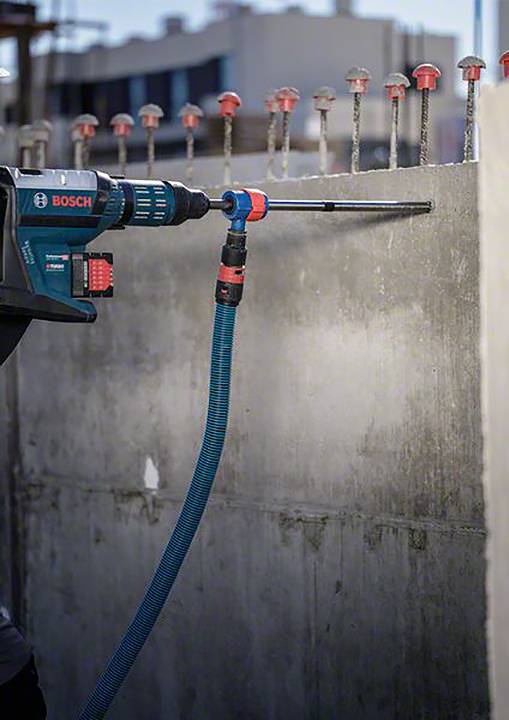 Eine Bohrmaschine wird benutzt, um Löcher in eine Betonwand zu bohren, möglicherweise für die Installation von Metallverankerungen.