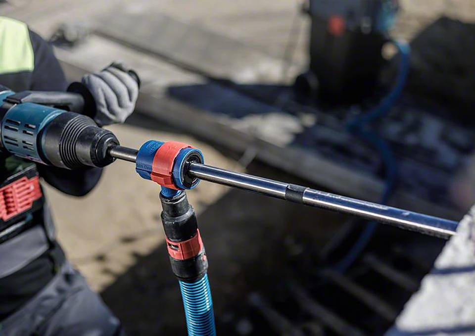 Person arbeitet mit Elektrowerkzeug an einer Baustelle. Bohrmaschine wird verwendet, um ein Loch in Beton zu bohren.