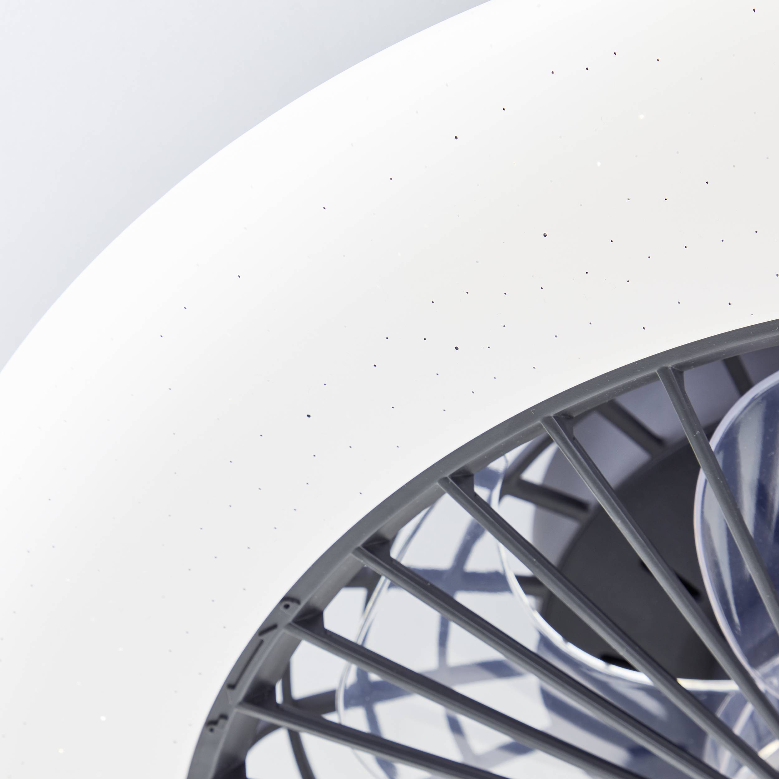 Ein weißer, runder Ventilator von oben fotografiert, zeigt seine rotierenden grauen Lamellen.