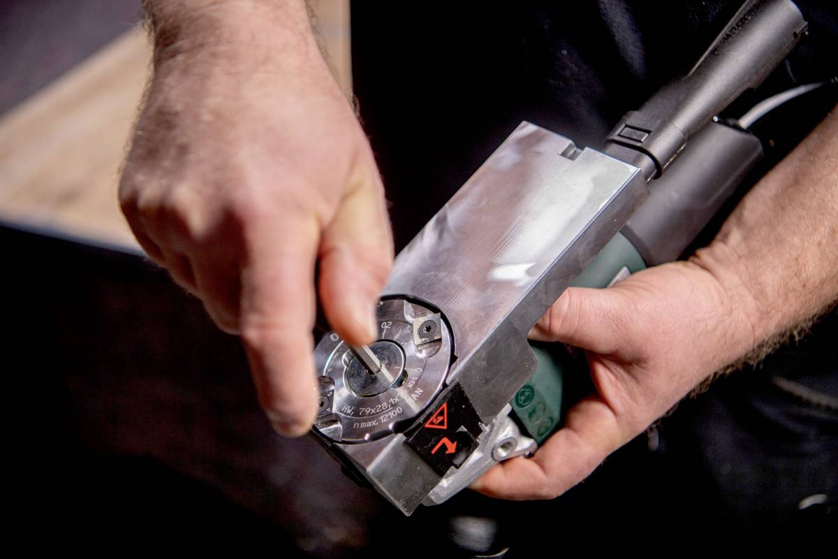 Nahaufnahme von Händen, die einen Leistungsregler an einem Elektrogerät einstellen. Das Zifferblatt zeigt verschiedene Einstellungen.