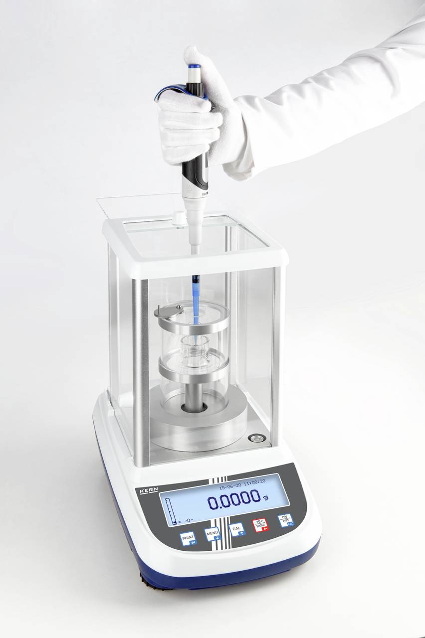 Eine Person füllt mit einer Pipette eine Flüssigkeit in einen Behälter auf einer digitalen Laborwaage.