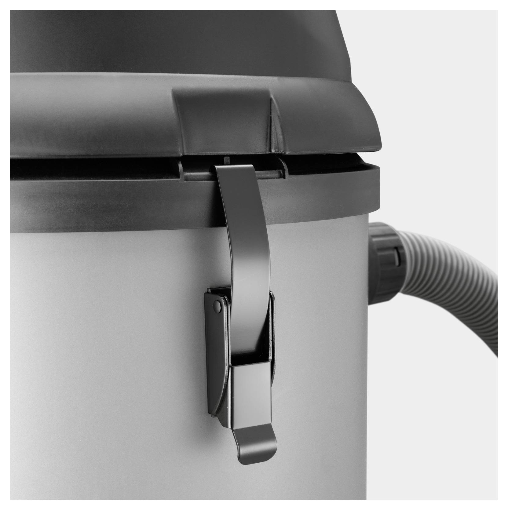 Eine Nahaufnahme eines schwarzen Riegels an einem zylindrischen Behälter, möglicherweise Teil eines Staubsaugers oder eines ähnlichen Geräts, mit einem Schlauch, der seitlich angeschlossen ist.