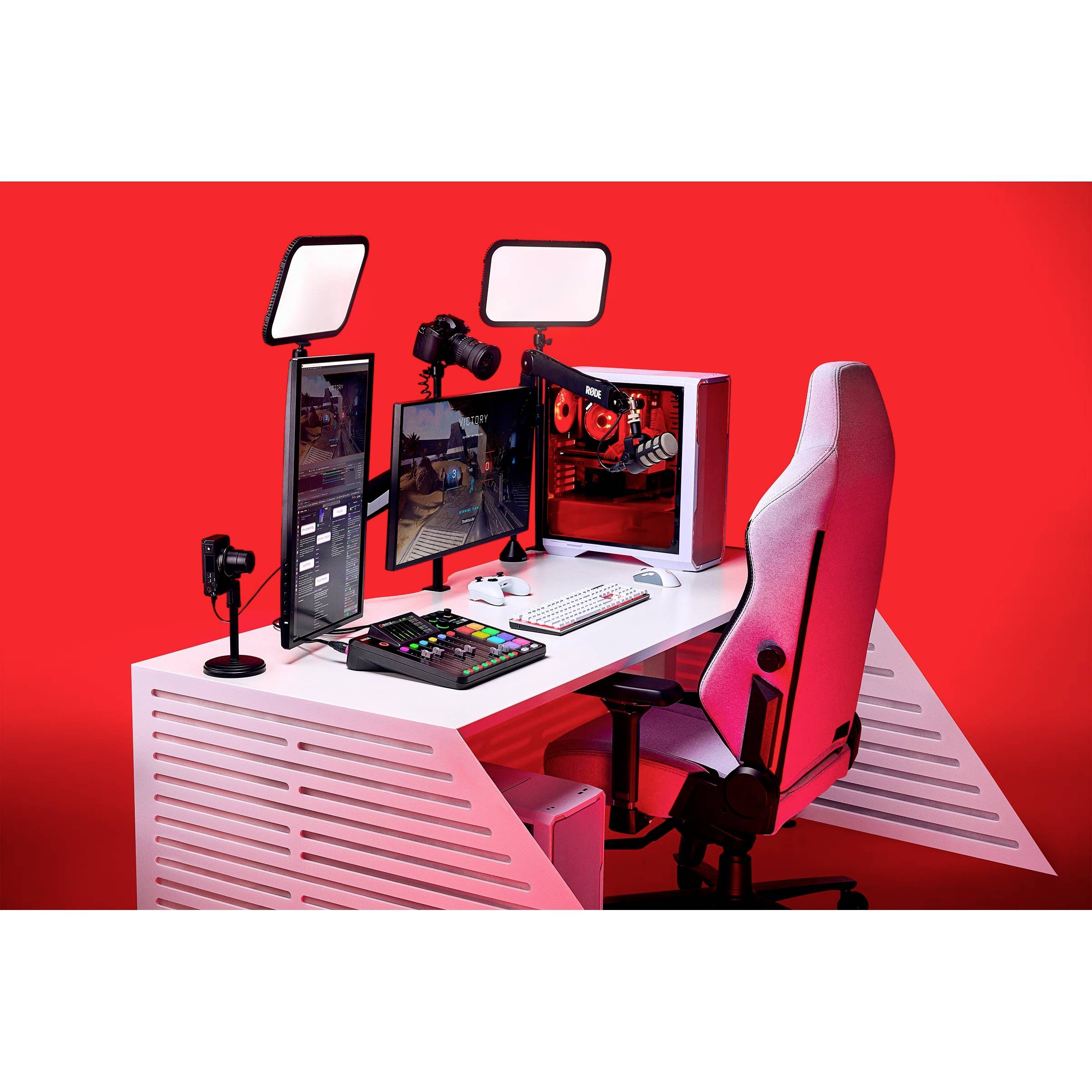 Ein moderner Gaming-Schreibtisch mit rot beleuchtetem PC, zwei Monitoren, Gaming-Tastatur und -Maus, sowie einem ergonomischen Stuhl.