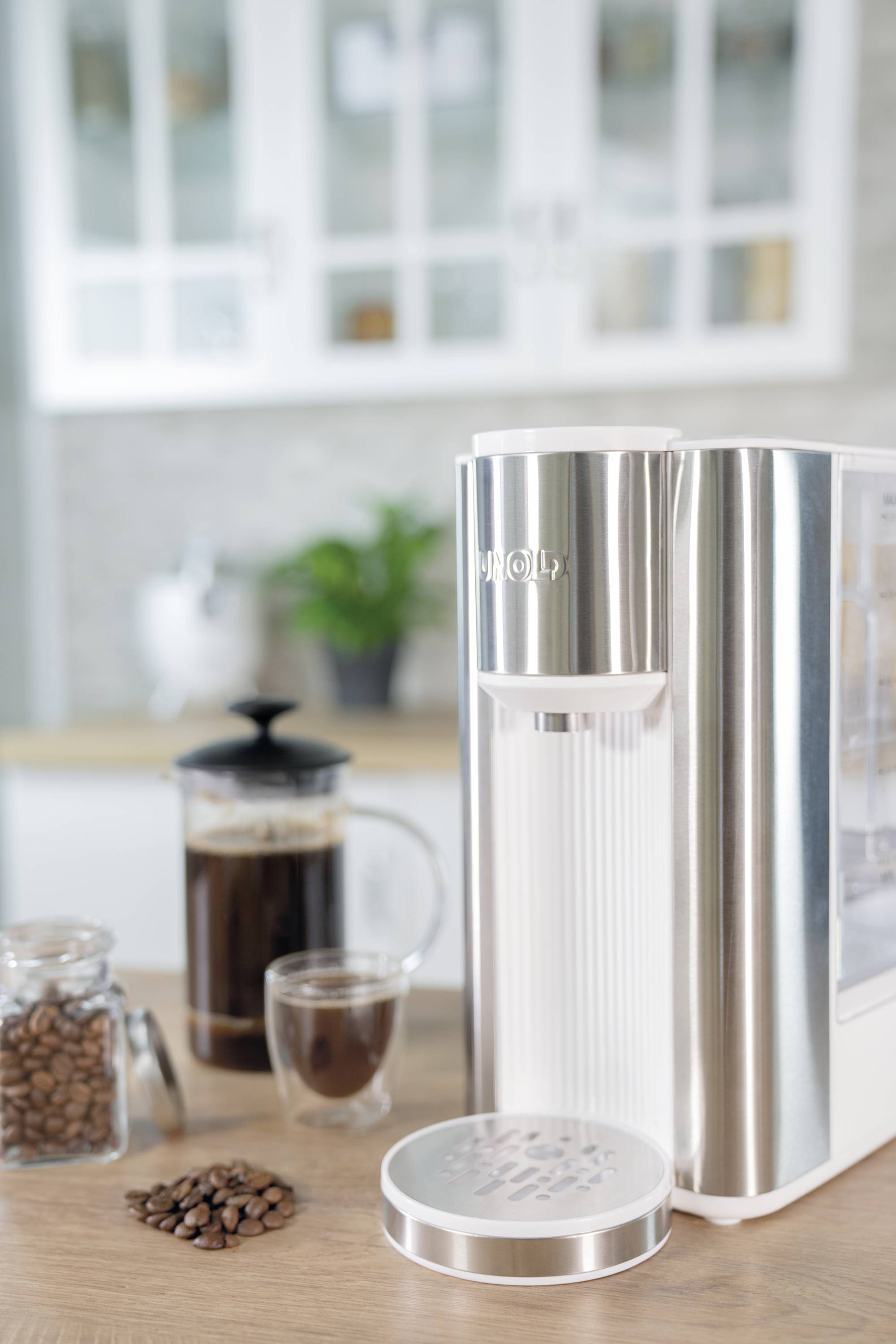 Eine Kaffeemaschine auf einer Küchenarbeitsplatte neben einer Kaffeepresse, einem Glas mit Kaffeebohnen und einer Tasse Kaffee.