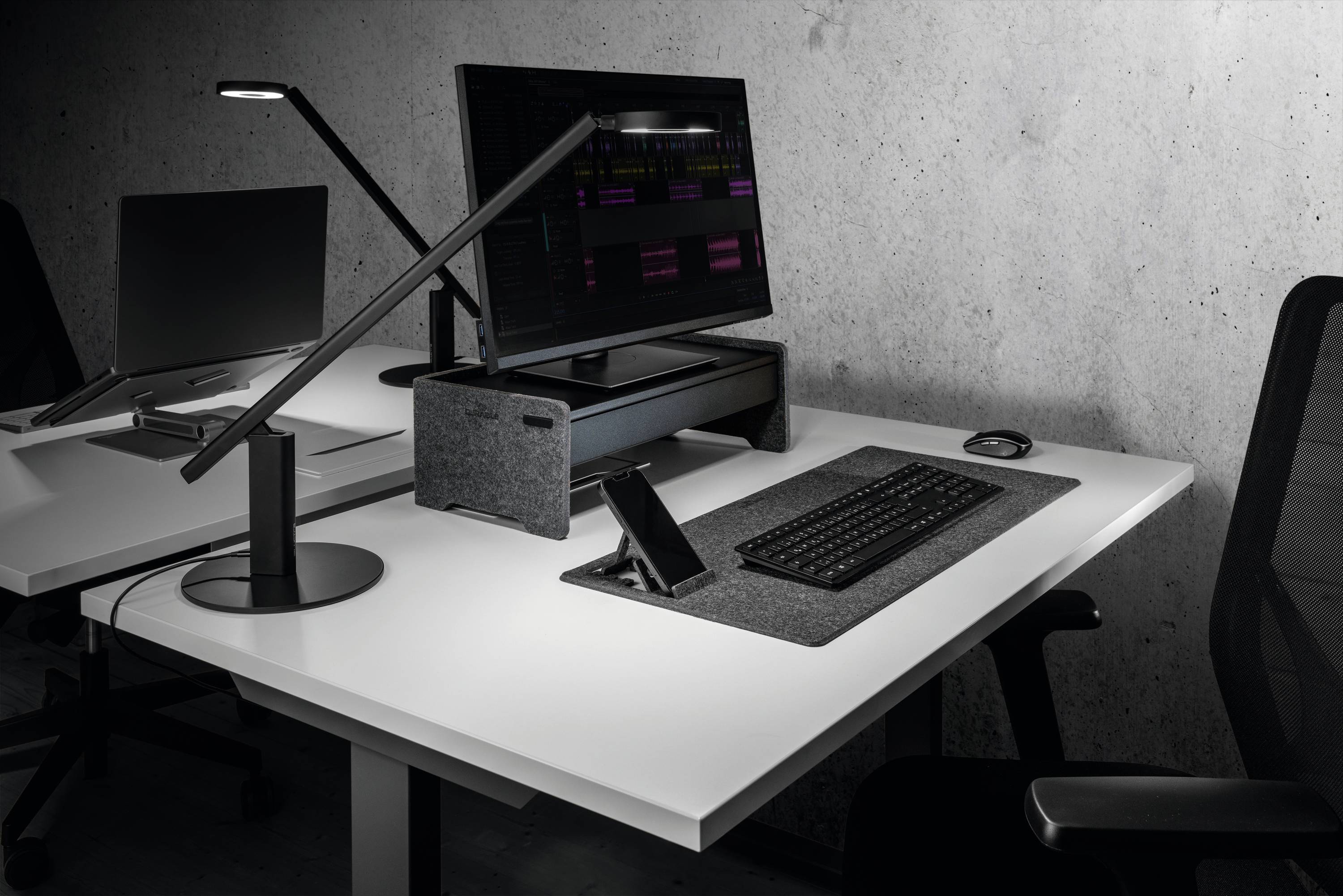 Ein moderner Schreibtisch mit Computer, Tastatur und Lampe. Der Schreibtisch ist ordentlich und minimalistisch gestaltet.