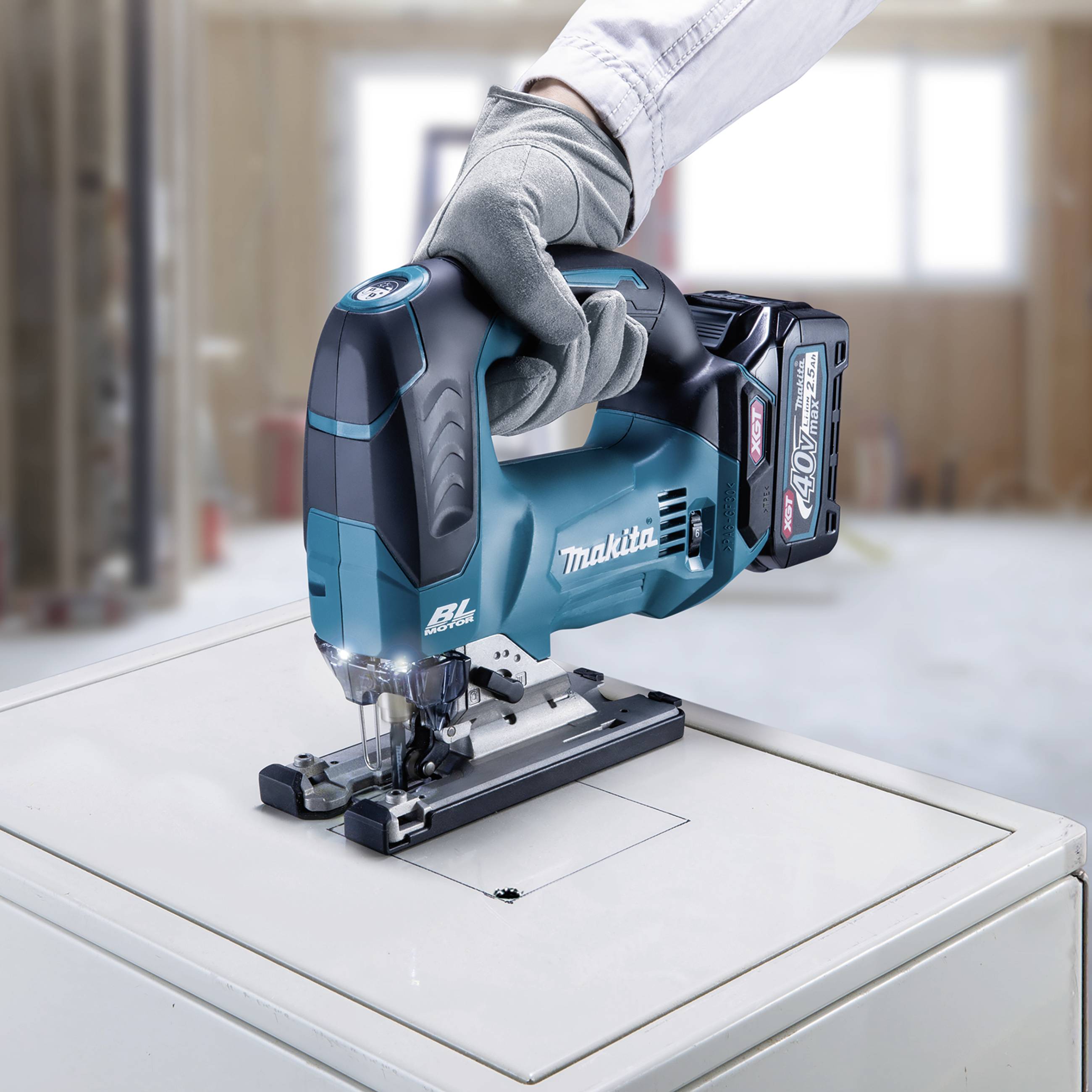 Eine Person mit Handschuhen bedient eine blaue elektrische Stichsäge, die eine gerade Linie in ein Metallstück schneidet.