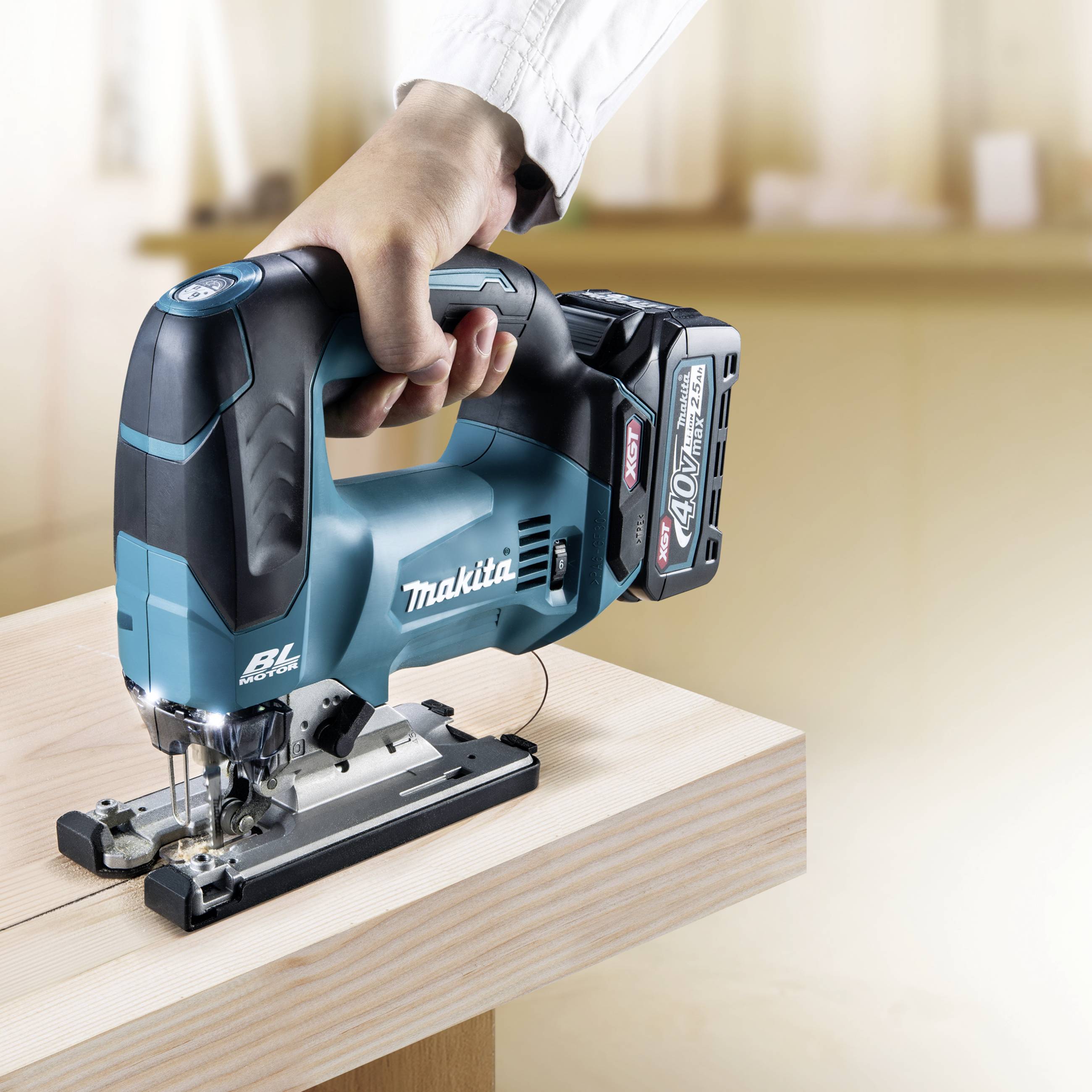 Person hält eine kabellose Stichsäge und schneidet Holz auf einer Werkbank.