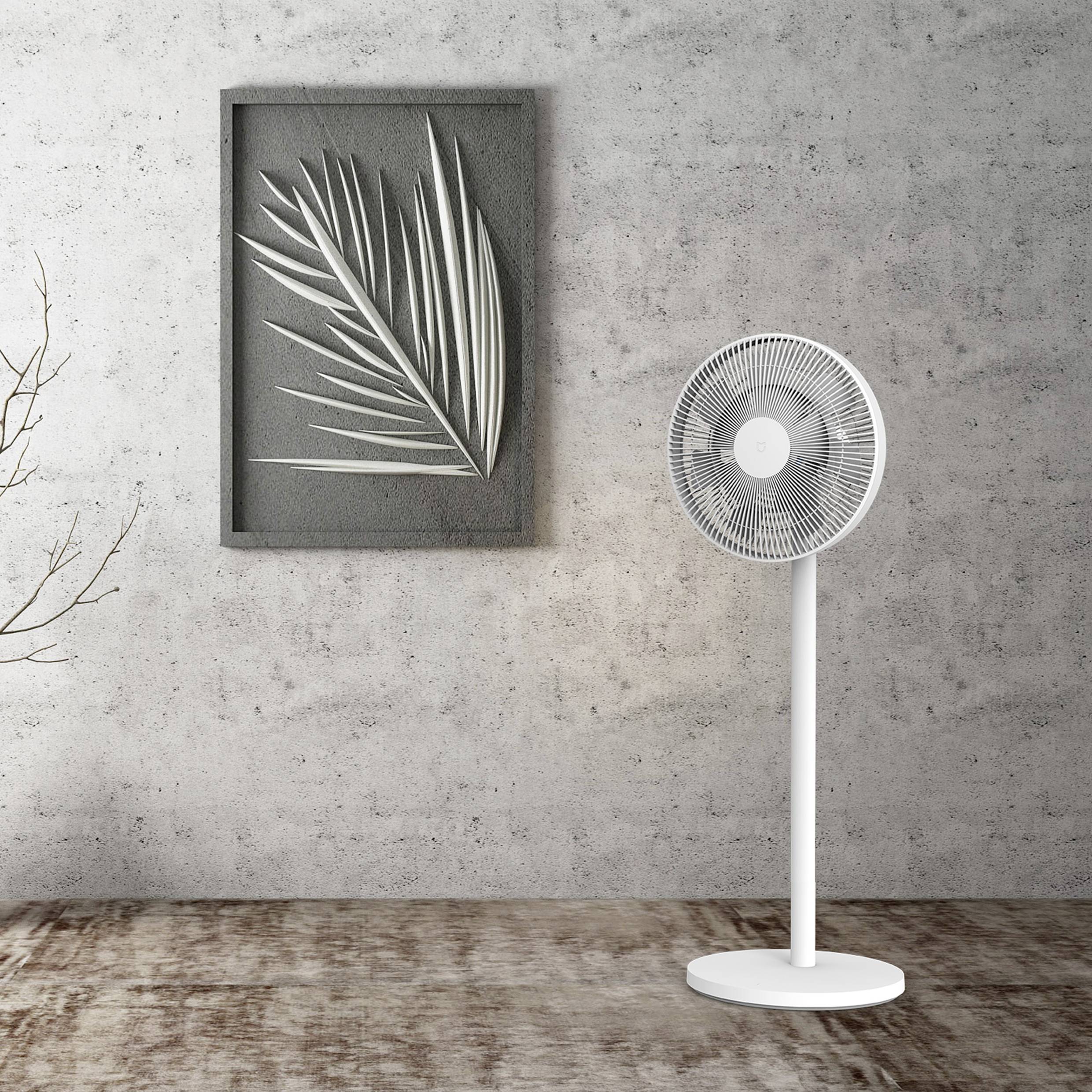 Ein weißer Standventilator steht in einem Raum mit einem Kunstwerk, das eine stilisierte Blätterdarstellung zeigt.