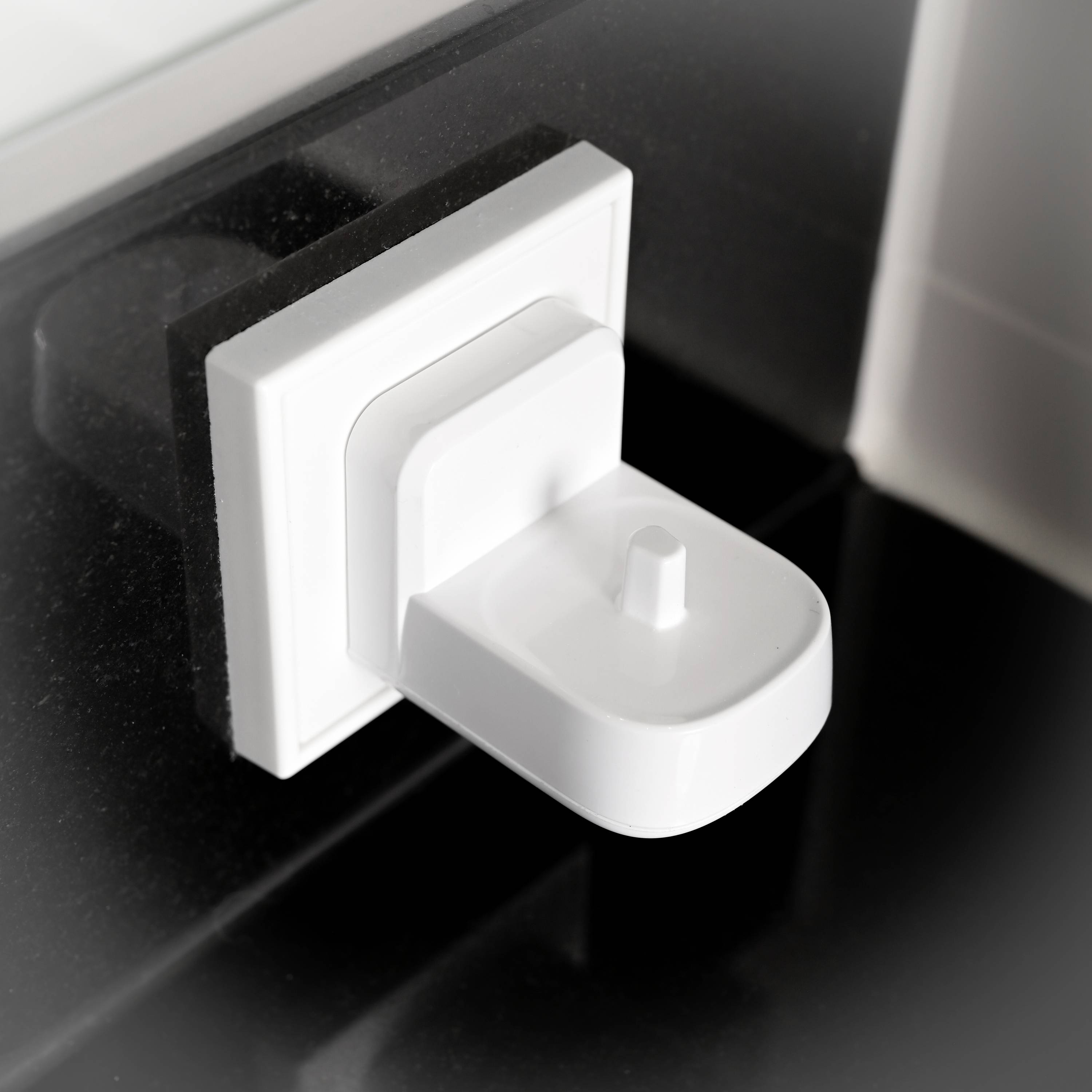 Weiße Steckdose an einer schwarzen Wand, mit modernem, minimalistischem Design.