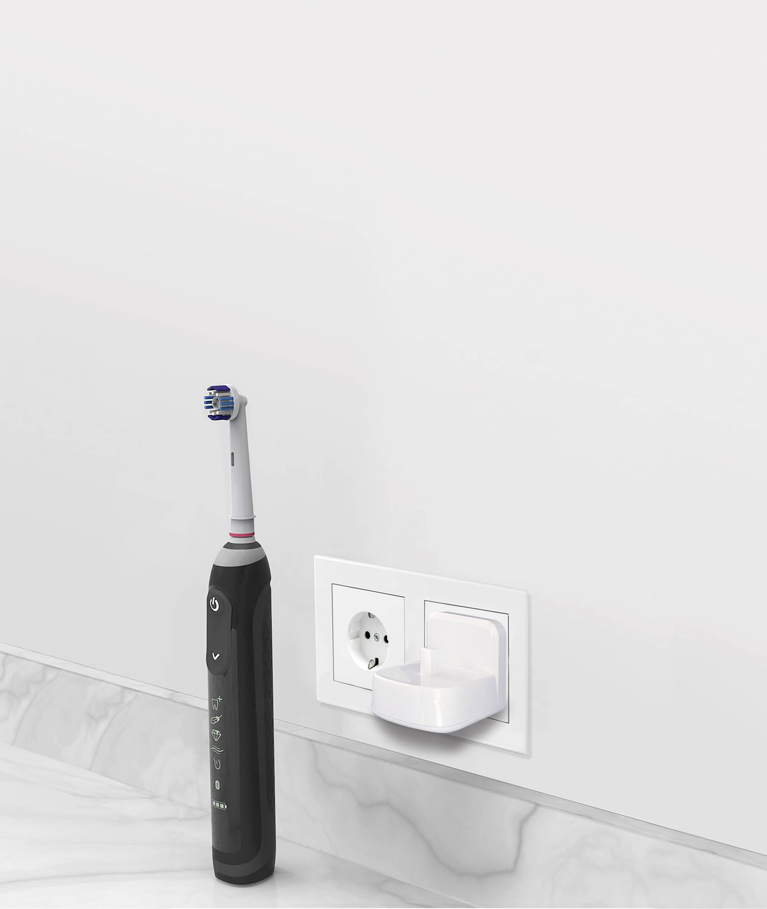 Elektrische Zahnbürste in schwarzer Farbe steht auf einem weißen Badezimmerwaschbecken neben einer Steckdose mit Ladegerät.