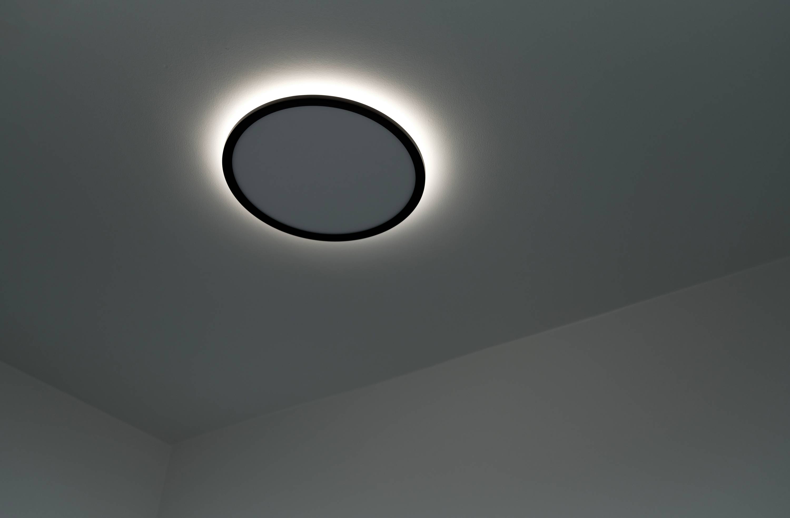 Eine dezente, runde Deckenleuchte mit weichem, gleichmäßigem Licht, montiert in einer modernen, minimalistisch gestalteten Raumdecke.