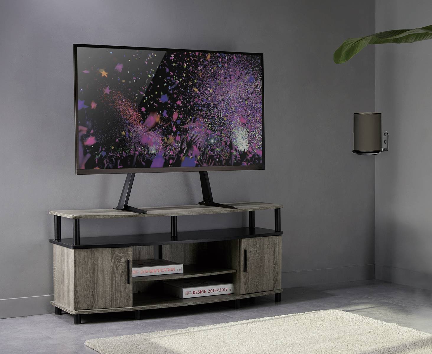 Ein Flachbildfernseher zeigt ein buntes Feuerwerk. Er steht auf einem modernen TV-Schrank aus Holz in einem minimalistisch eingerichteten Raum.