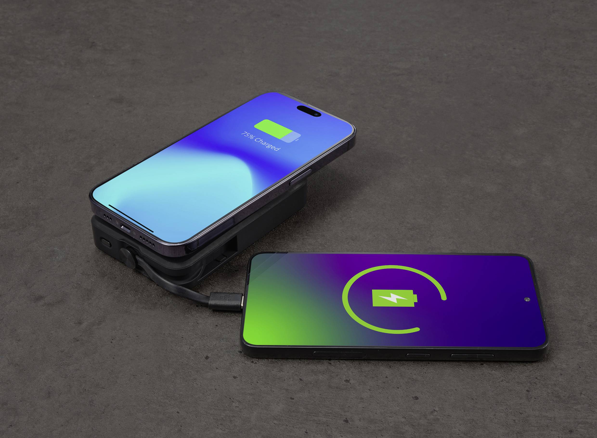 Zwei Smartphones auf einem Tisch; das linke Gerät wird über ein Kabel vom rechten aufgeladen.