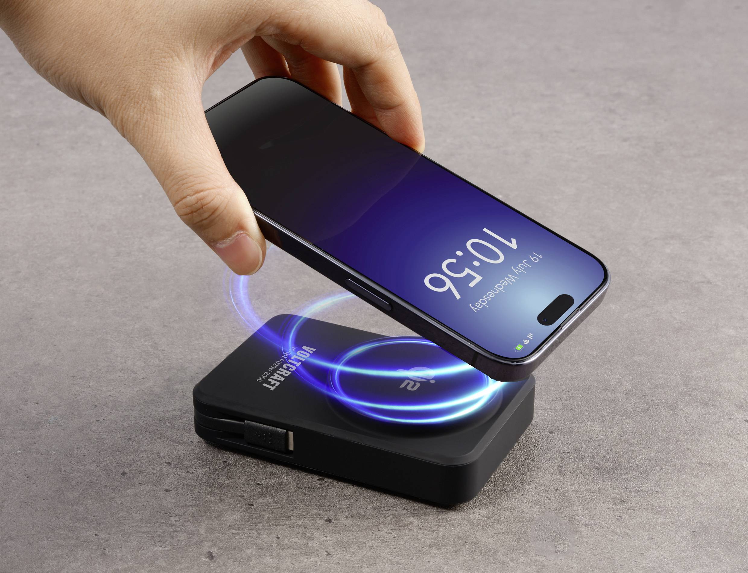Ein Smartphone wird über einem kabellosen Ladegerät gehalten, das eine blaue Ladeanzeige zeigt. Das Smartphone-Display zeigt '10:56'.