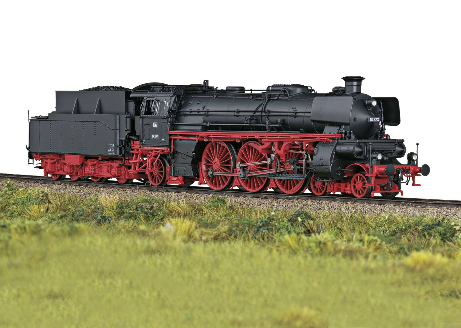 Ein Modell einer historischen Dampflokomotive mit schwarzem Kessel und roten Rädern steht auf einem Gleis vor einem grasbewachsenen Hintergrund.