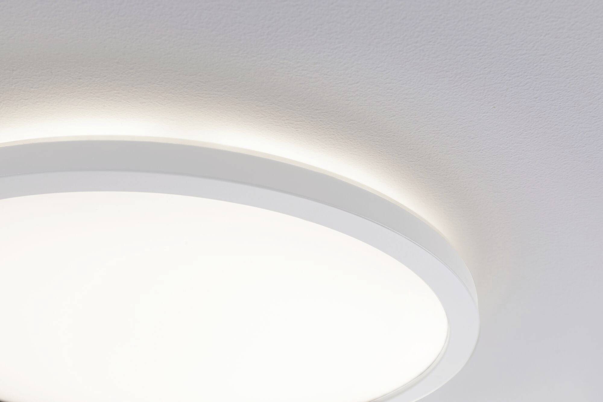 Runde, weiße Deckenlampe strahlt sanftes Licht auf helle Decke. Minimalistisches Design.