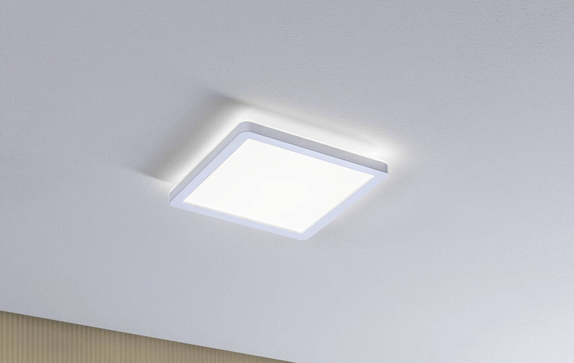 Quadratische LED-Deckenleuchte mit weißem Rahmen leuchtet in einem Raum mit weißer Decke.