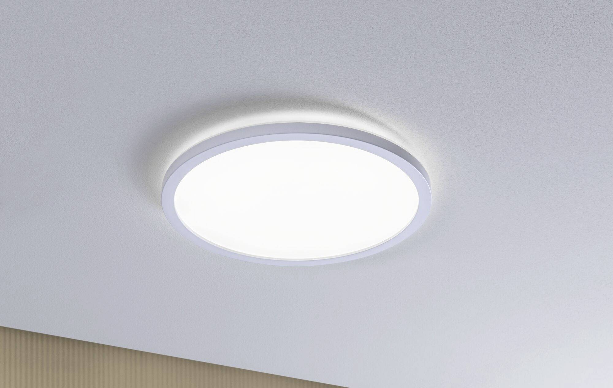 Runde, weiße Deckenleuchte mit schlichter Leuchtkraft, montiert an einer hellen Decke in moderner Inneneinrichtung.