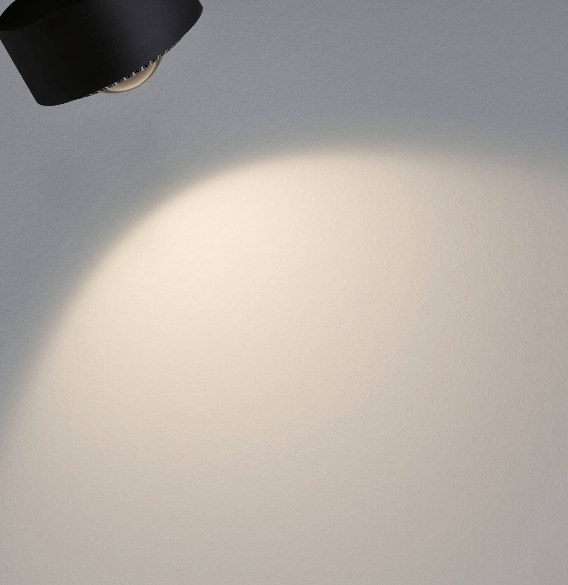 Eine Lampe beleuchtet eine Wand, wobei der Lichtkegel nach unten gerichtet ist.
