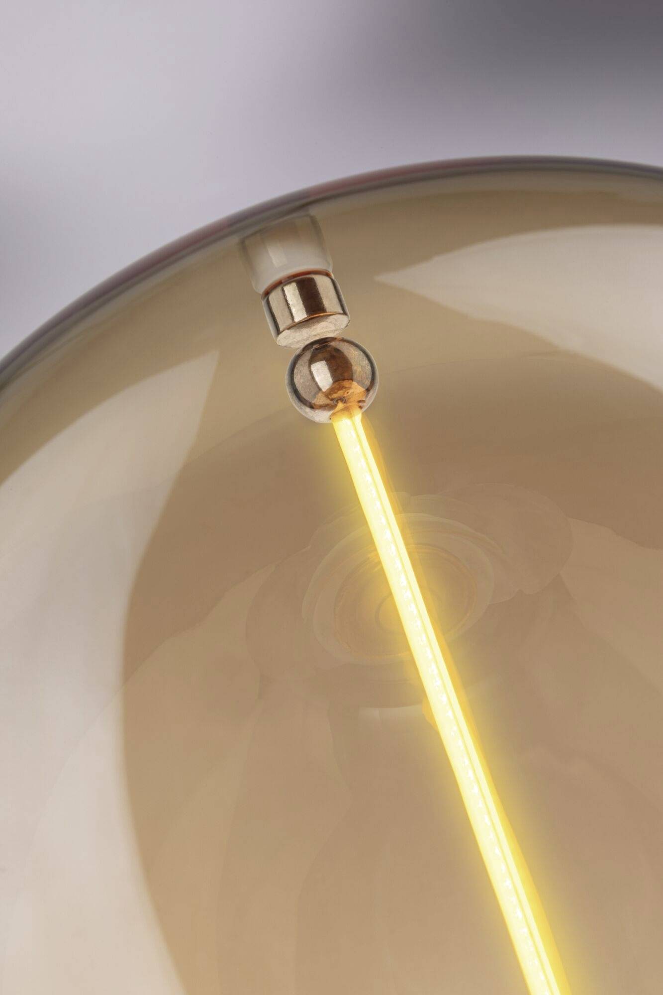 Nahaufnahme einer leuchtenden Glühbirne mit sichtbarem Filament, das warmes Licht abstrahlt. Klarer Glasballon mit sanften Reflexionen.