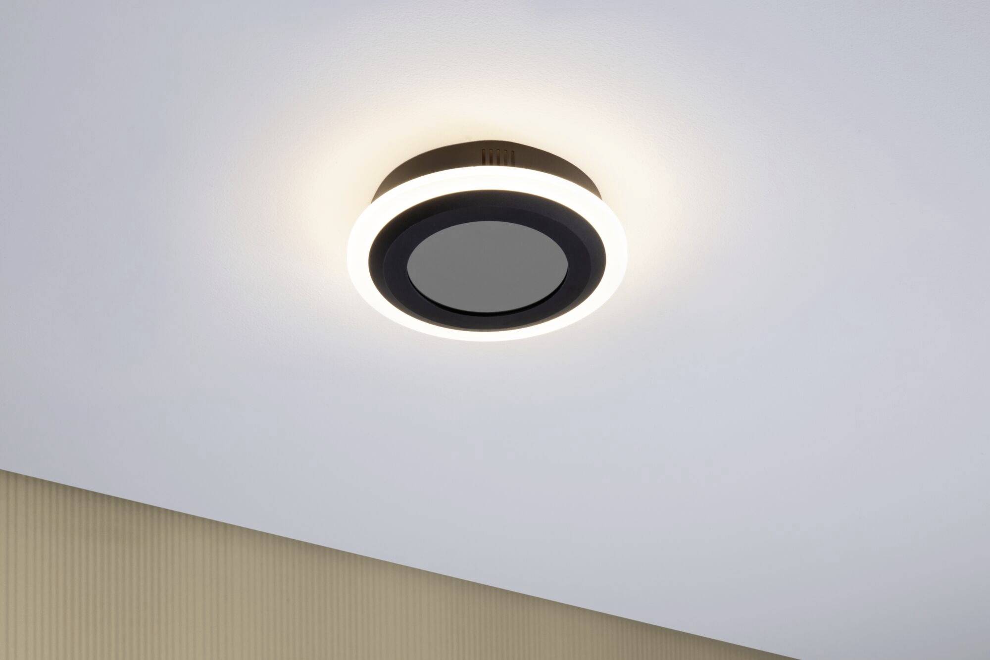 Deckenleuchte in modernem Design mit kreisförmigem, leuchtendem Rand an einer weißen Decke, verbreitet warmes Licht.