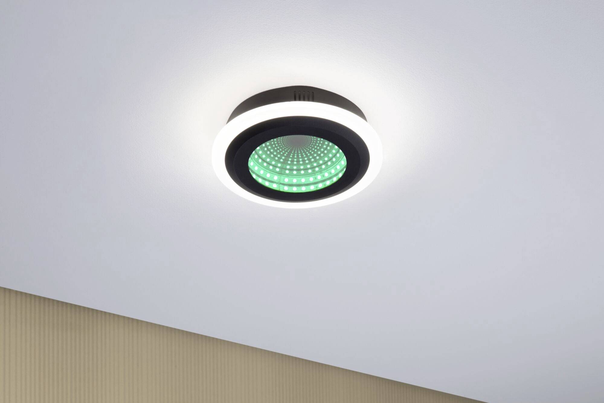 Eine moderne, runde Deckenleuchte mit grün leuchtenden Elementen an der Unterseite, montiert an einer hellen Decke in einem zeitgenössischen Raum.
