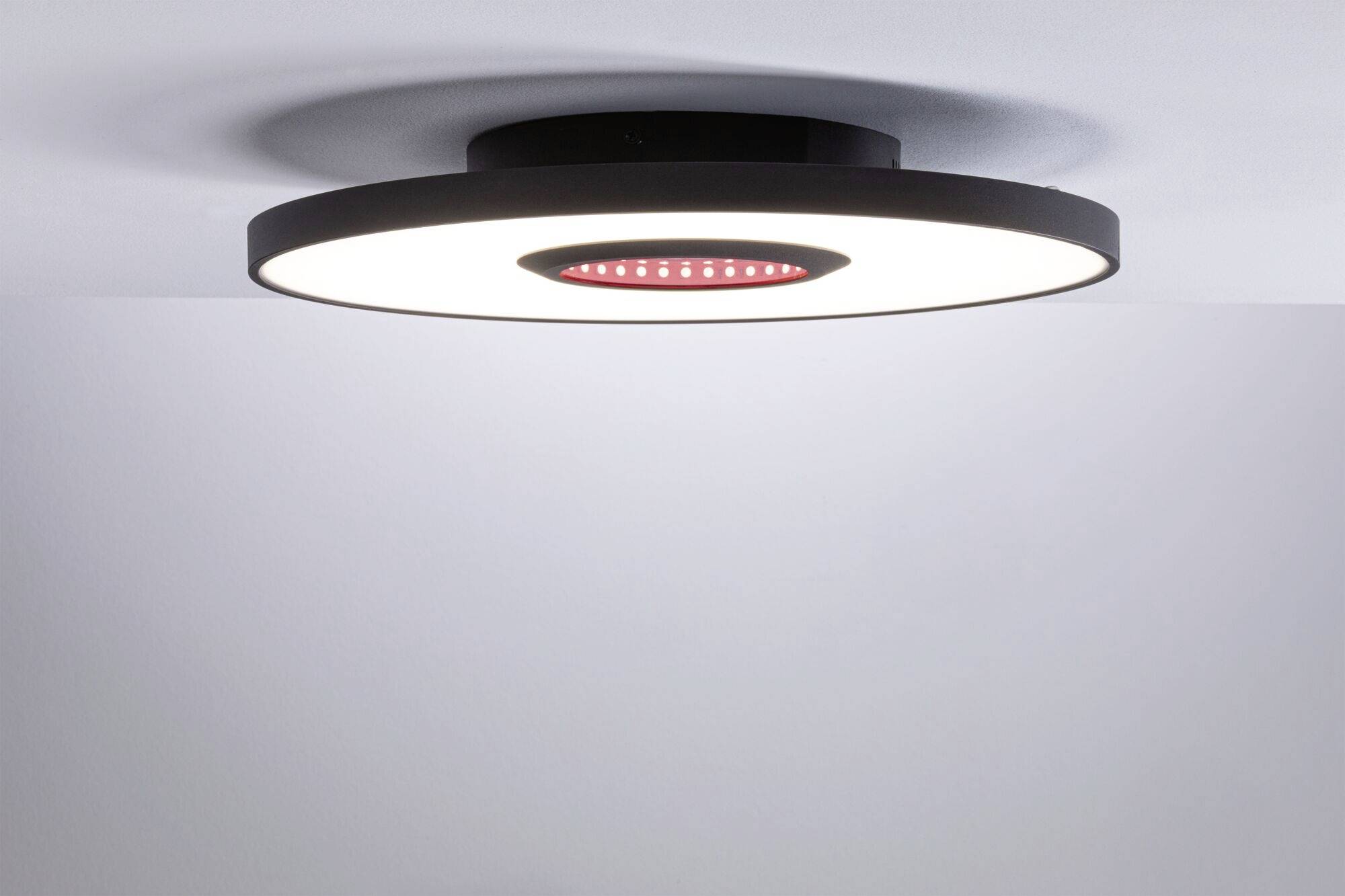 Runde Deckenleuchte mit schwarzem Rand und zentralem roten Element, montiert an einer weißen Decke.