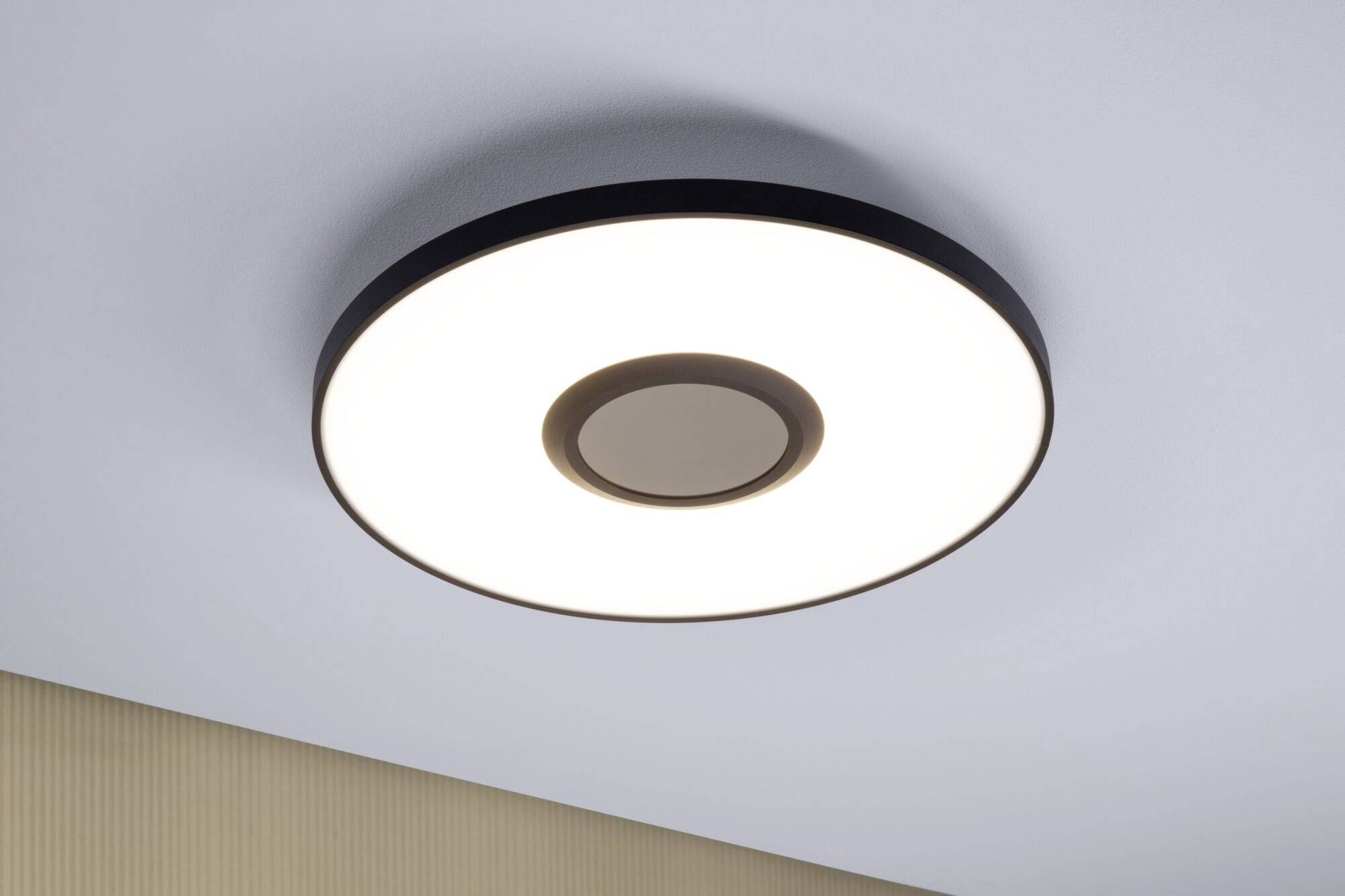 Runde Deckenleuchte mit schwarzem Rand und zentralem Kreis, beleuchtet einen Raum, modern und schlichtes Design.