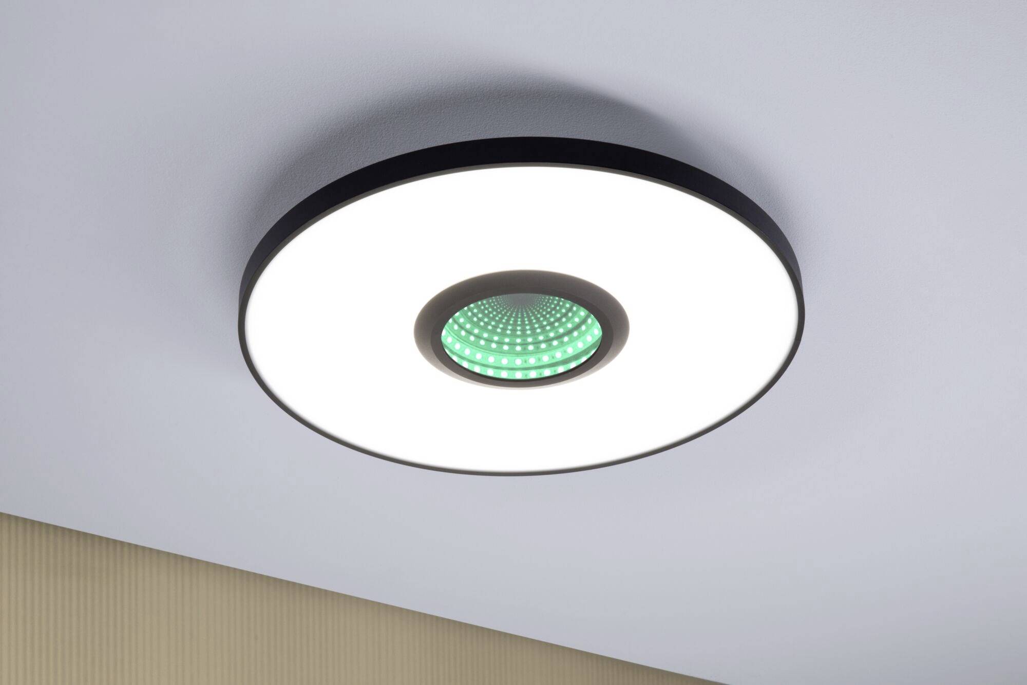 Runde Deckenleuchte mit zentralem grünem Lichtelement in modernem Raum. Beleuchtet gleichmäßig die Umgebung.