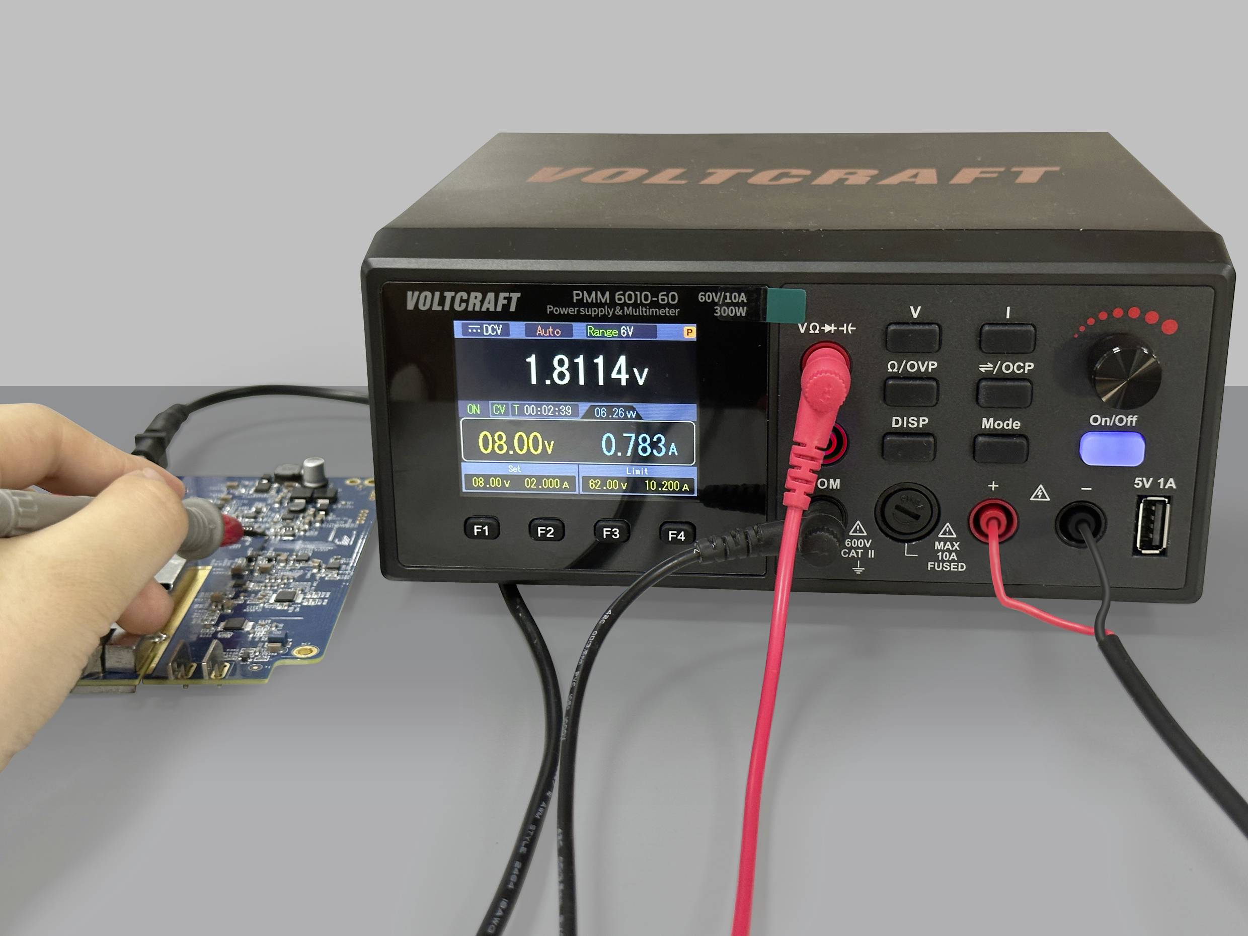 Eine Person misst mit einem Lötkolben die Spannung auf einer elektronischen Platine. Ein Messgerät zeigt verschiedene Werte an.