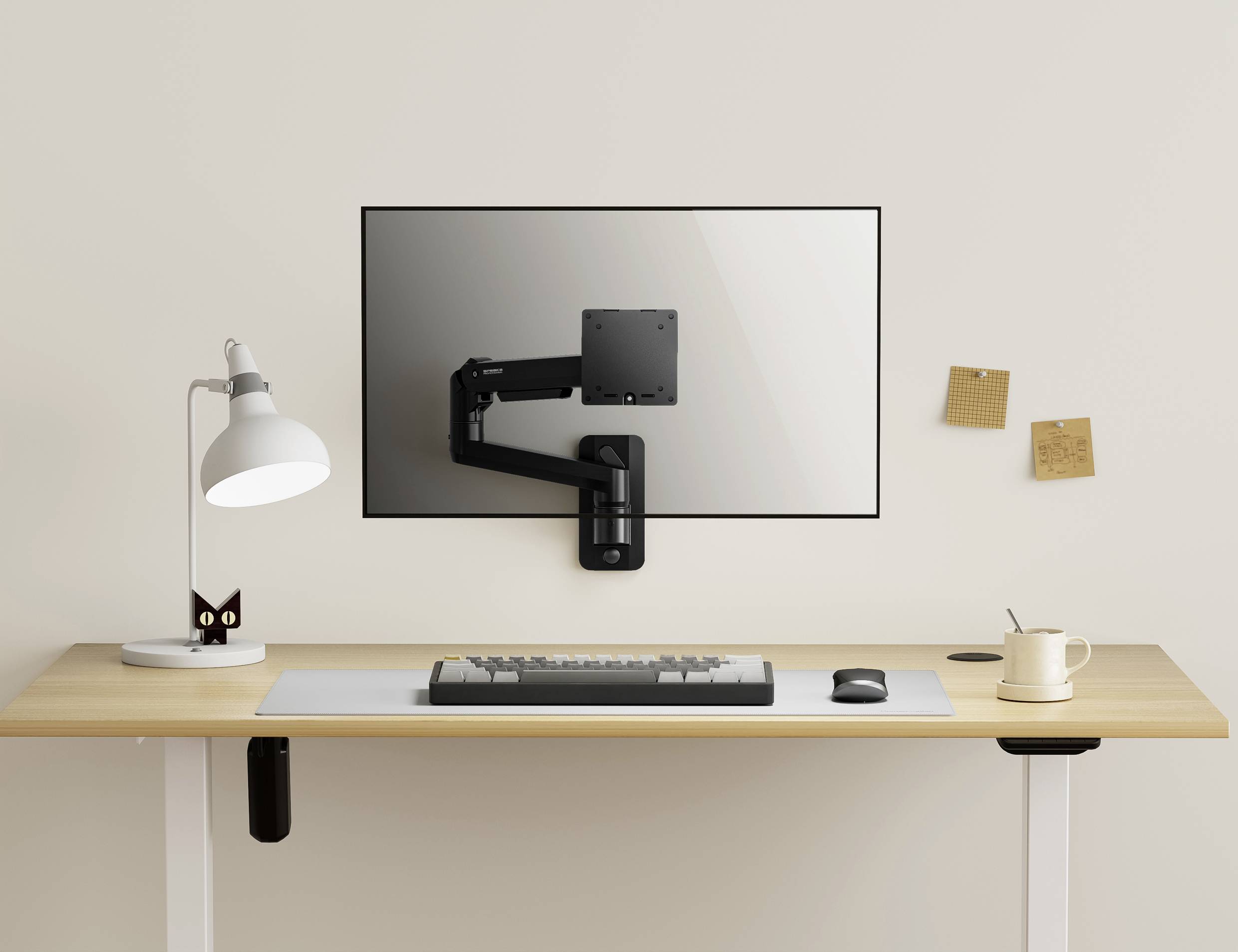Ein minimalistischer Schreibtisch mit einer Lampe, einem weißen Mauspad, einer Tasse und einer Tastatur. Ein Monitorarm ohne Monitor ist an der Wand befestigt.
