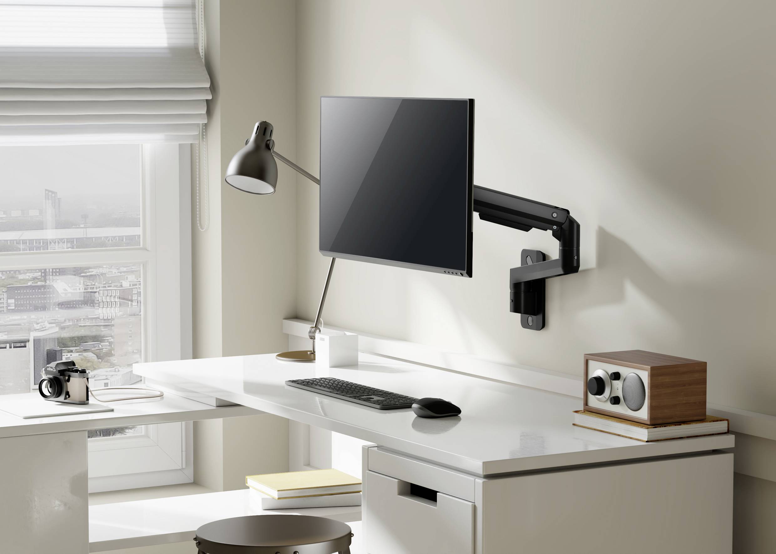 Ein moderner, aufgeräumter Arbeitsplatz mit einem Monitor an einem flexiblen Arm, einer Lampe, Tastatur, Maus und Büroklammern auf einem weißen Tisch.