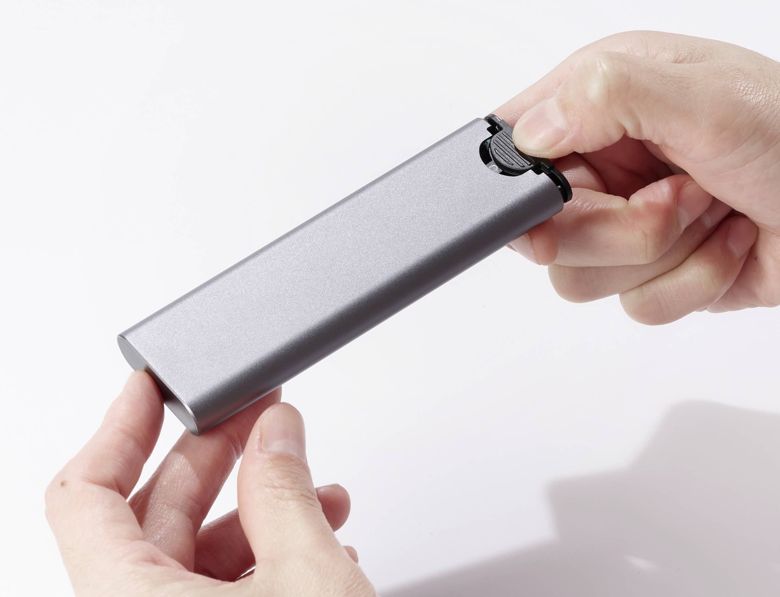 Zwei Hände halten eine graue, rechteckige Powerbank mit einem USB-Ausgang an der Spitze, bereit zum Anschluss eines Geräts.