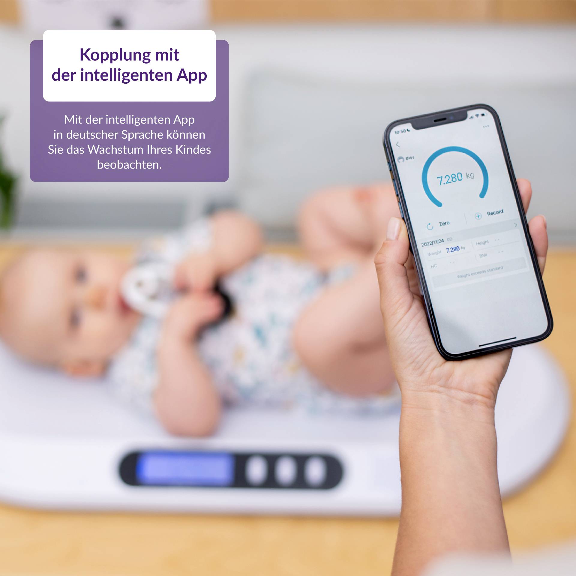 Person hält ein Smartphone mit einer App, die das Gewicht eines Babys anzeigt. Baby liegt auf einer digitalen Waage im Hintergrund.