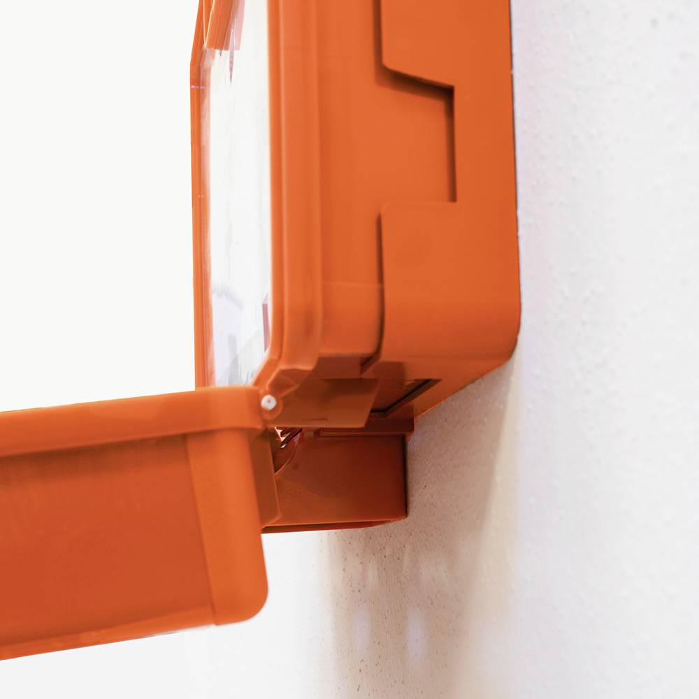 Ein rotes Erste-Hilfe-Set an einer weißen Wand, leicht geöffnet, bereit für den Zugriff auf medizinische Ausrüstung.